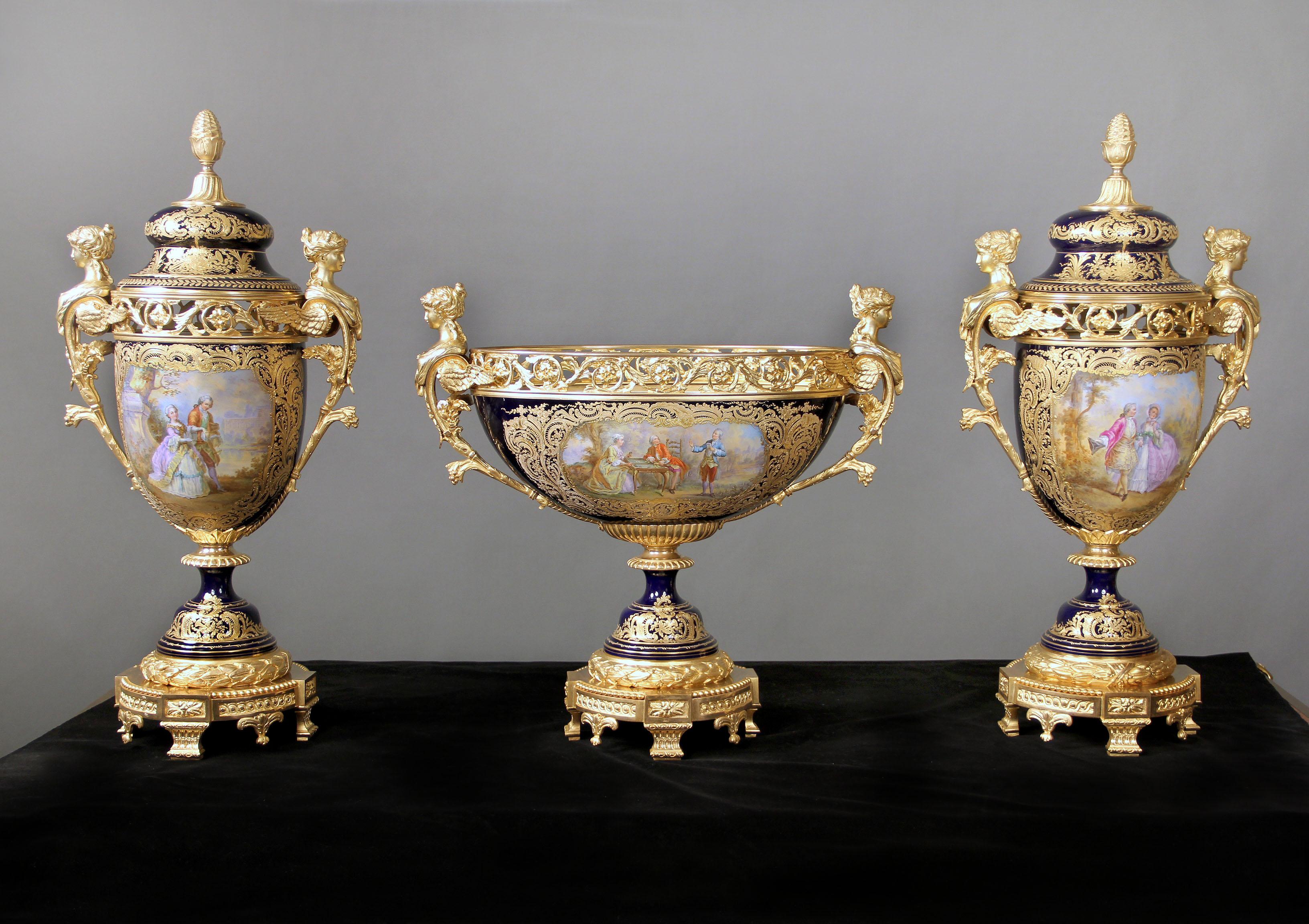 Une très impressionnante garniture de trois pièces en porcelaine de style Sèvres de la fin du XIXe siècle, en bronze doré et bleu cobalt. 

L'impressionnante pièce centrale présente une bordure perforée représentant des feuillages en bronze doré