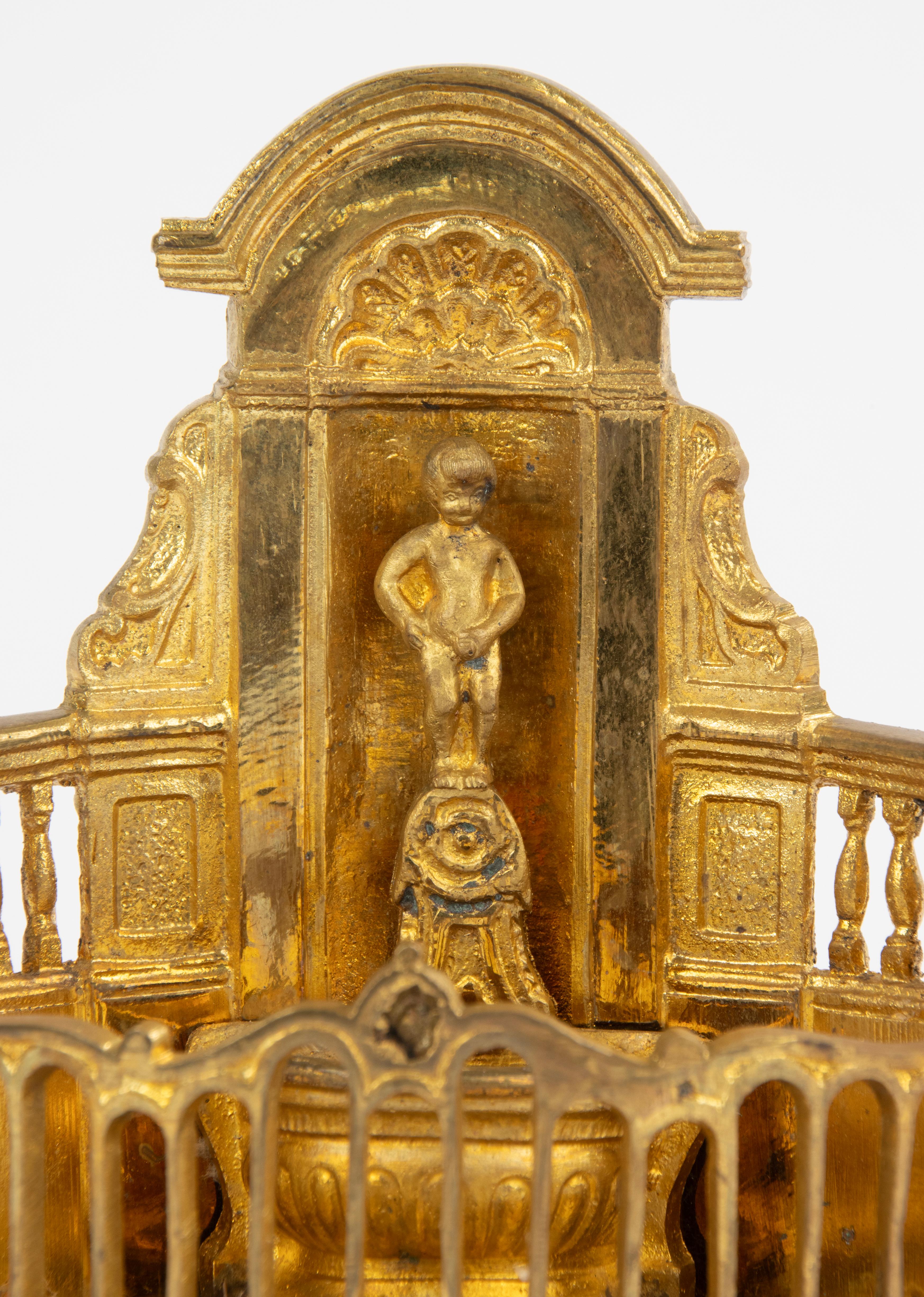 Bellissima versione in miniatura in bronzo dorato di uno dei più famosi monumenti belgi e simbolo della città di Bruxelles. Manneken Pis. Su un basamento di marmo. Stampigliato sul retro. 

L'originale è di Hiëronymus Duquesnoy de Oudere, realizzato
