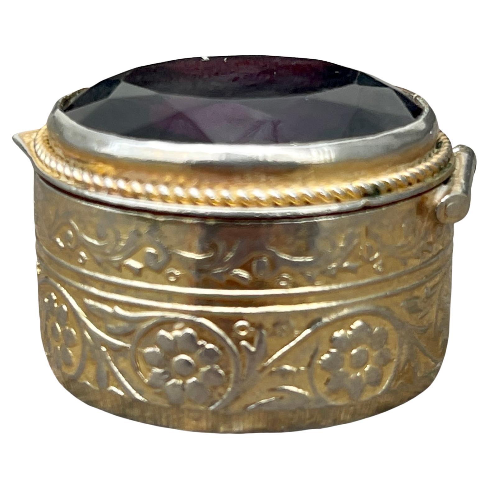 Late 19th Century gilt metal pill box with beveled burgundy glass top.