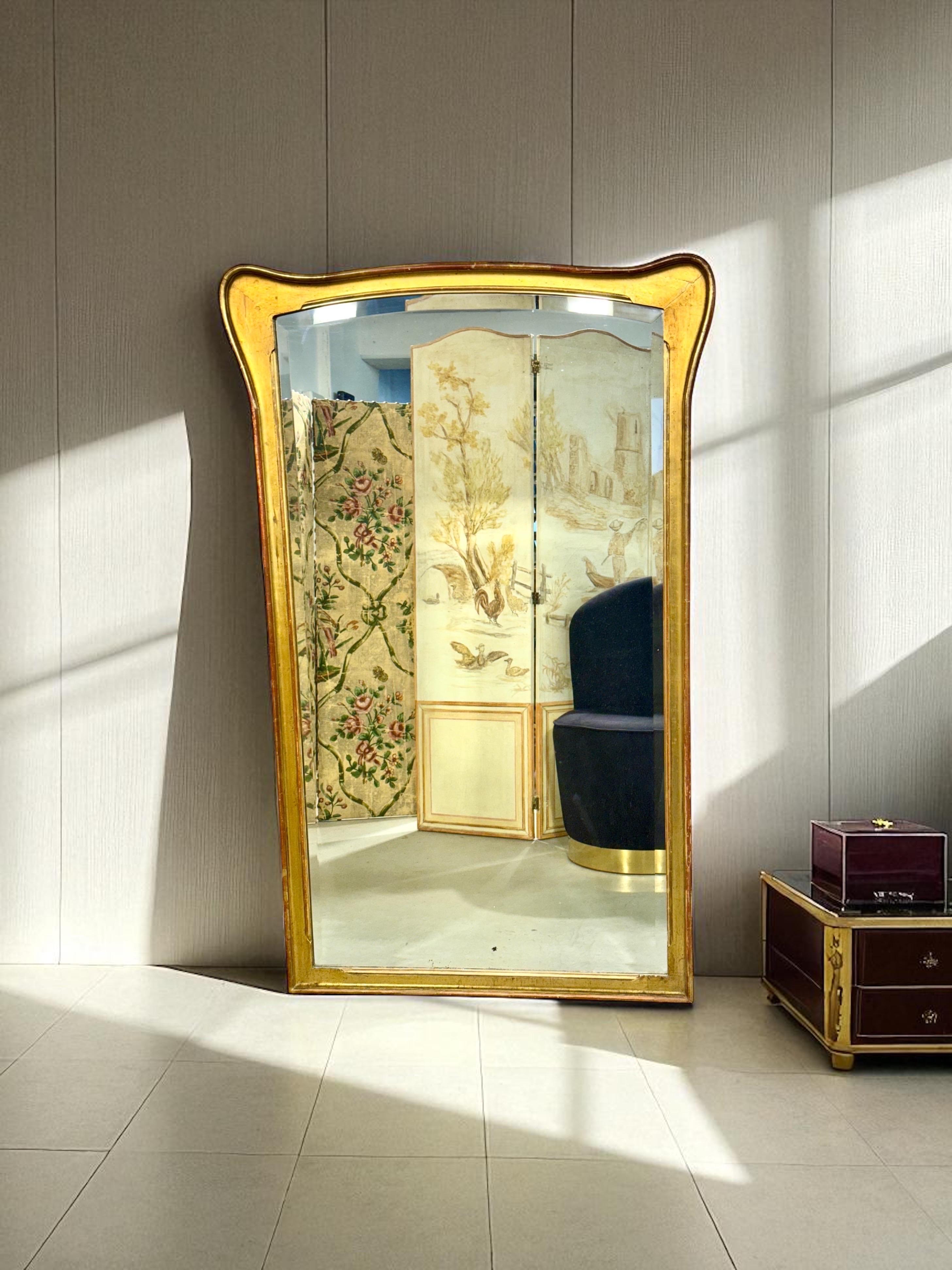 This elegant giltwood mirror, dating from the late 19th century to around 1900, beautifully embodies the refined craftsmanship and decorative sensibilities of its time. Its distinctive frame, with gently flared upper corners and softly rounded