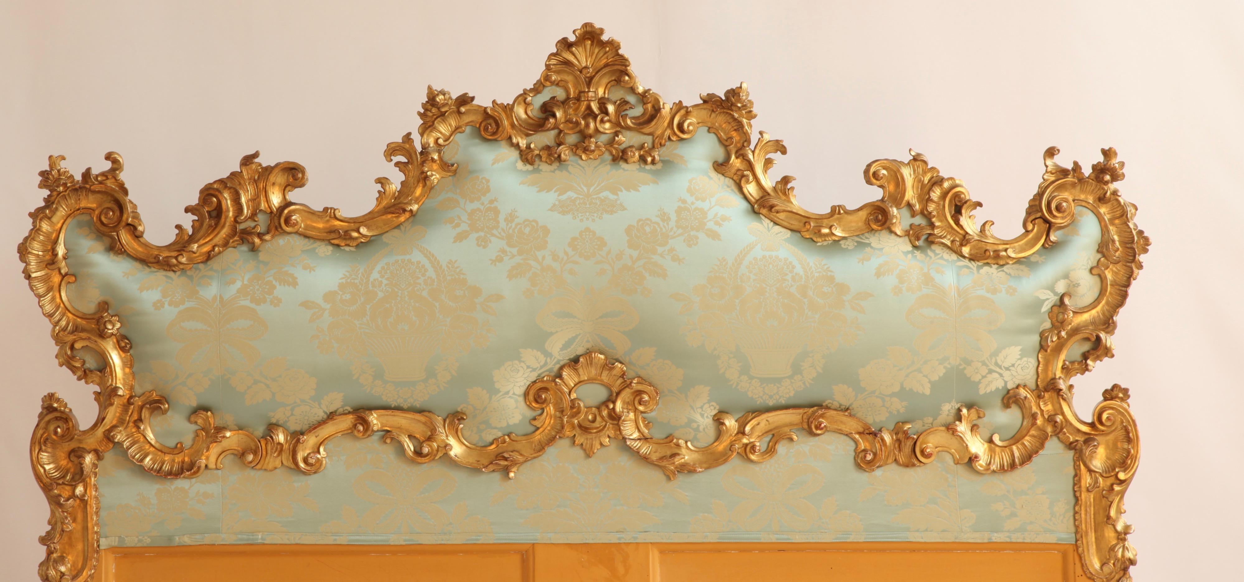 Antique Italian large giltwood headboard from late 19th century.
Reupholstered with a sea green/light blue silk damask.
Fine carving with details of Louis XV scrolls, shells and flowers all around.

    