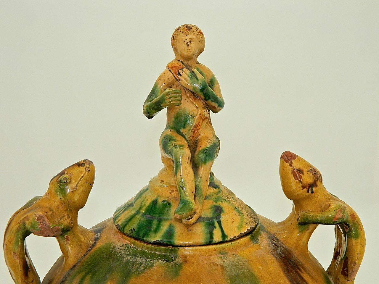 This whimsical late 19th century glazed large-mouth Majolica urn features two near life-size salamanders as handles, crowned by a delicately proportioned conical top with a seated figure.

Found in the town of Perelada in the province of Girona,