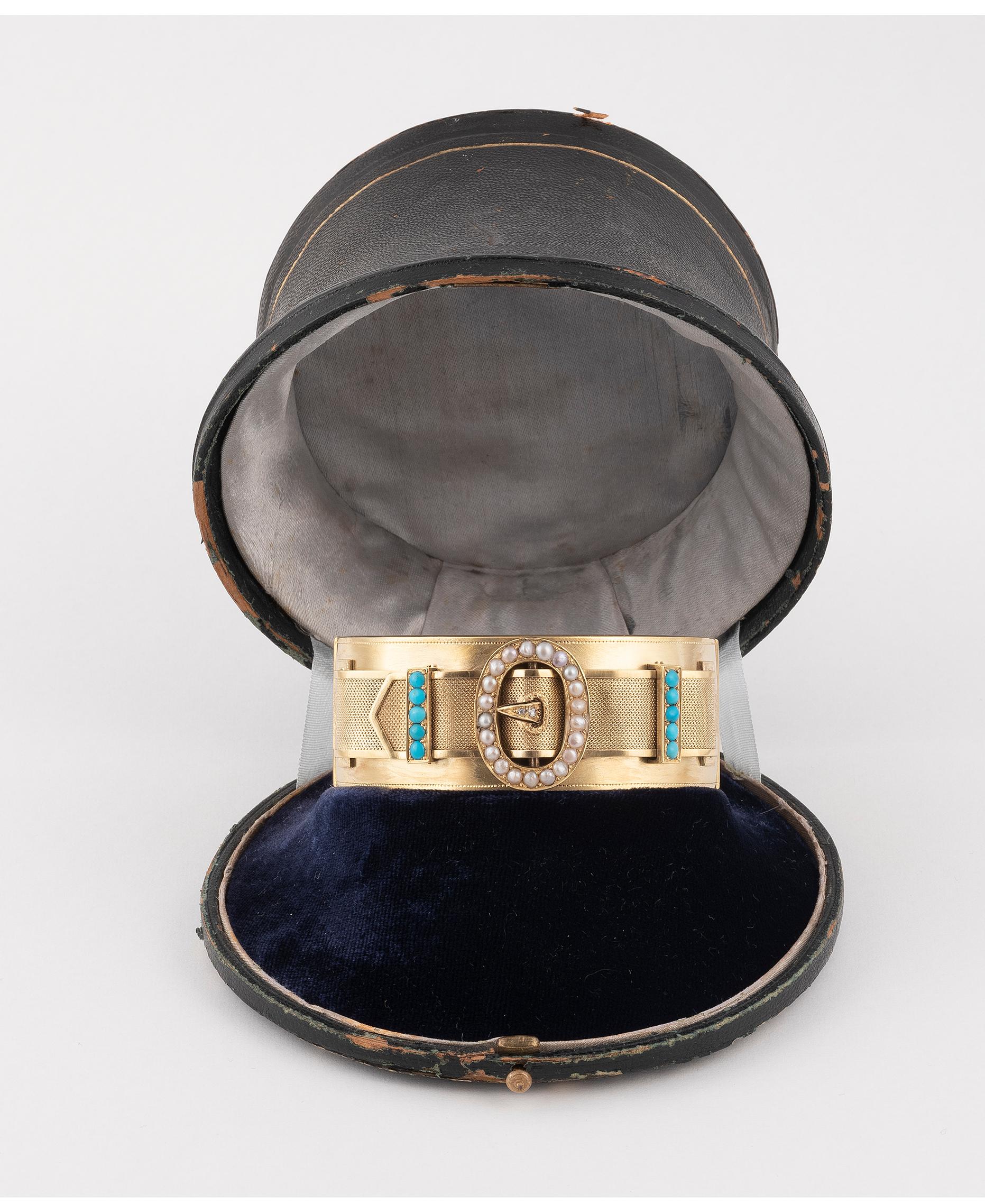 A late 19th century gold hinged bangle, with rose-cut diamond, split pearl and turquoise buckle motif.French re-strike mark. Inner diameter 5.8cms. 49.8gms.With case. 
Width 2.4cms.