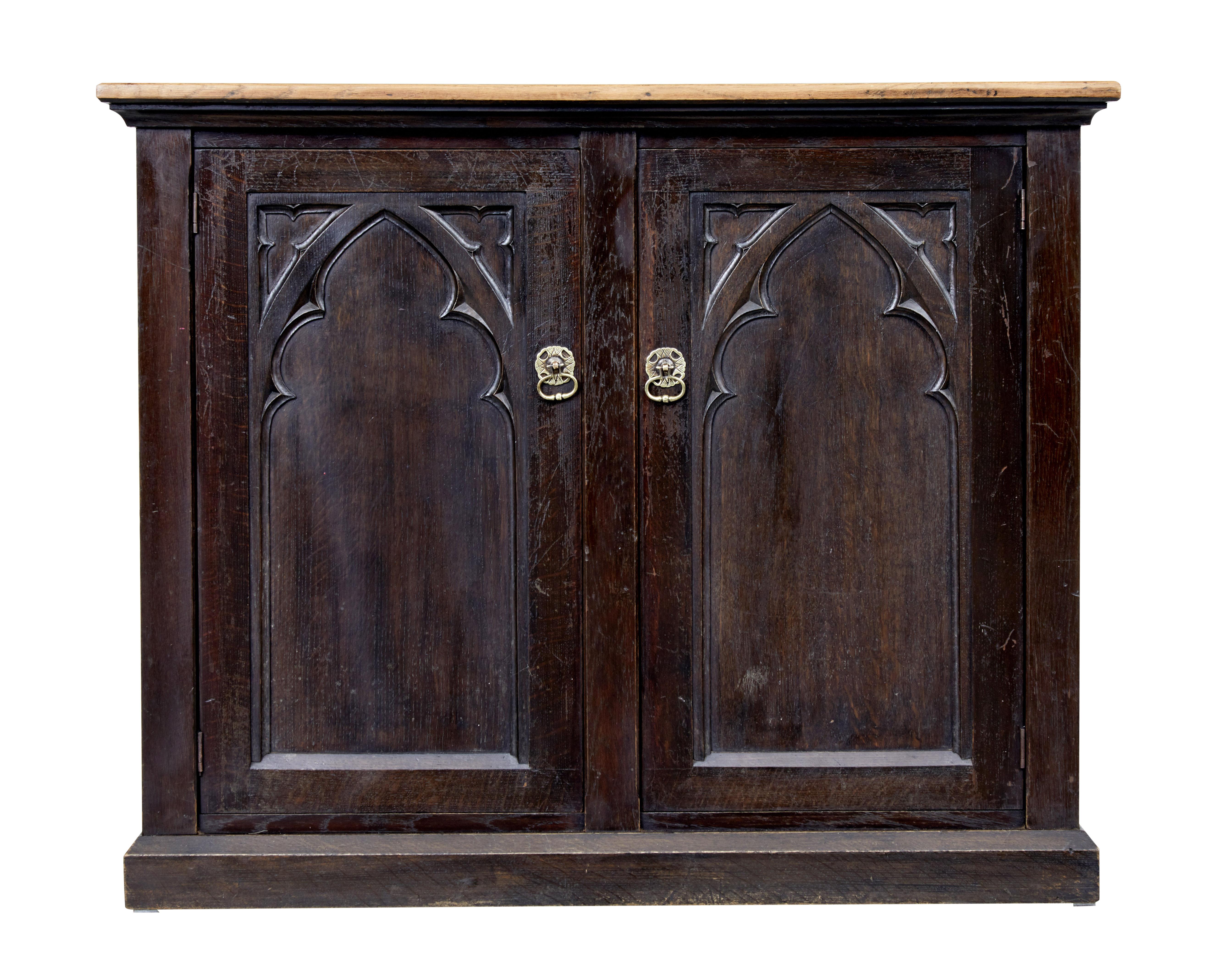 Late 19th century Gothic Revival oak cupboard circa 1890.

Oak cupboard with contrasting light oak top surface. Below which a double door cupboard with applied tracery moulding opening to 2 shelves. Similar applied tracery to the