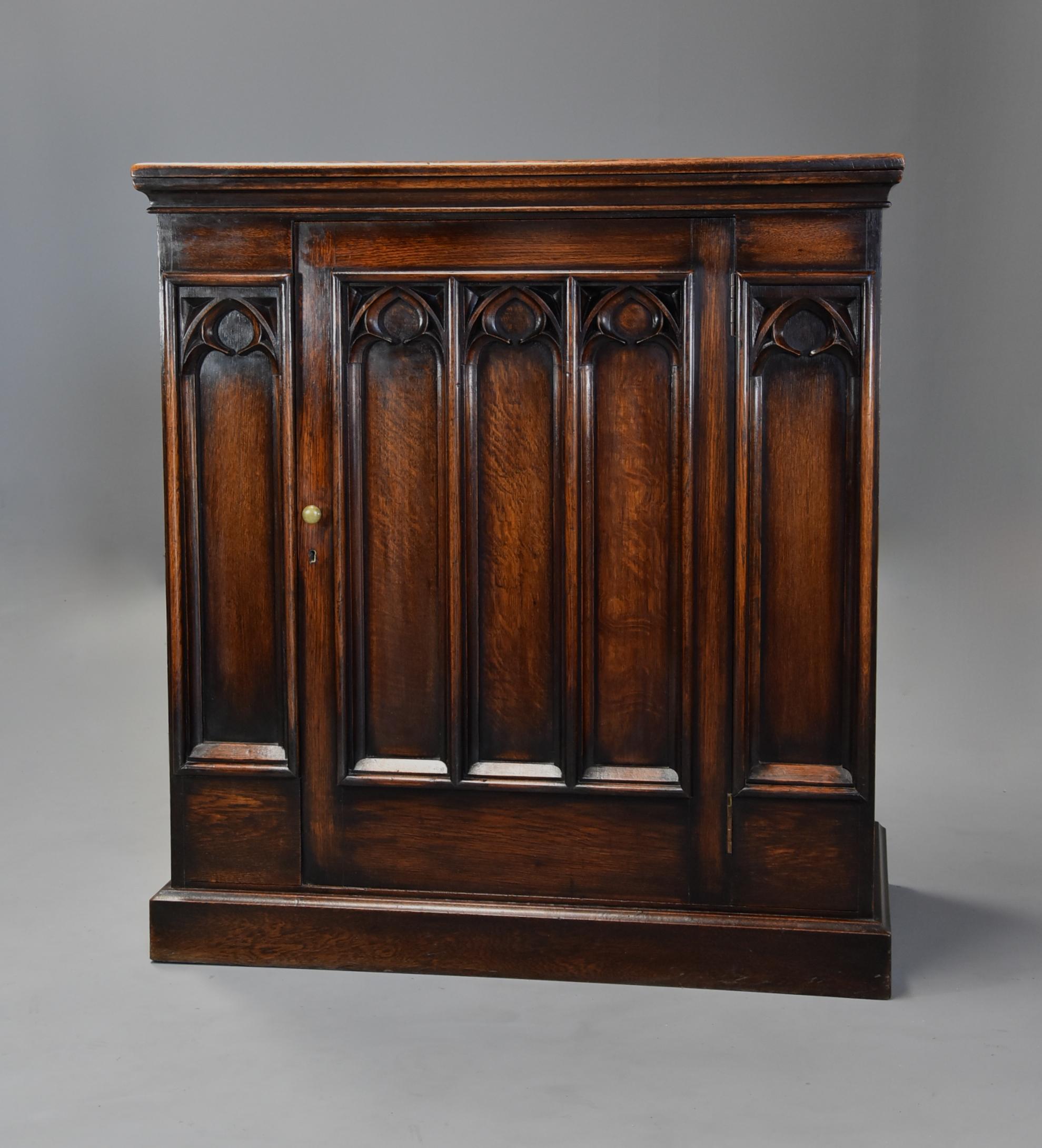 A late 19th century Gothic style oak cupboard.

This cupboard consists of a solid oak top with a molded edge leading down to a single door consisting of three carved Gothic style panels with brass knob handle and a Gothic style carved panel to
