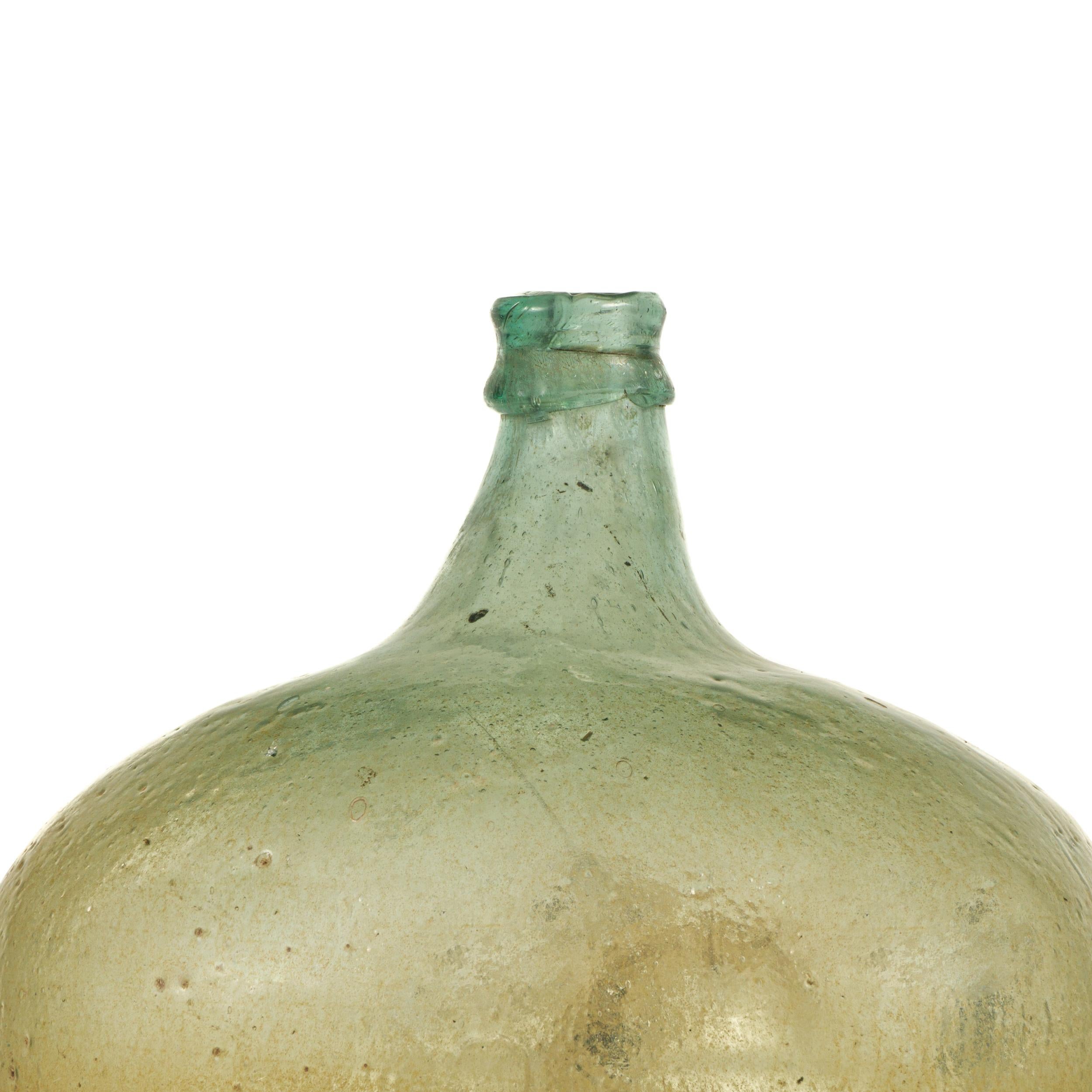 Late 19th century Green mouth blown glass Demijohn from Southern Mexico.
Originally used as a traditional containers mainly for wine storage and transport.
Today, they can be used as decorative accessories anywhere in the home, mainly because of