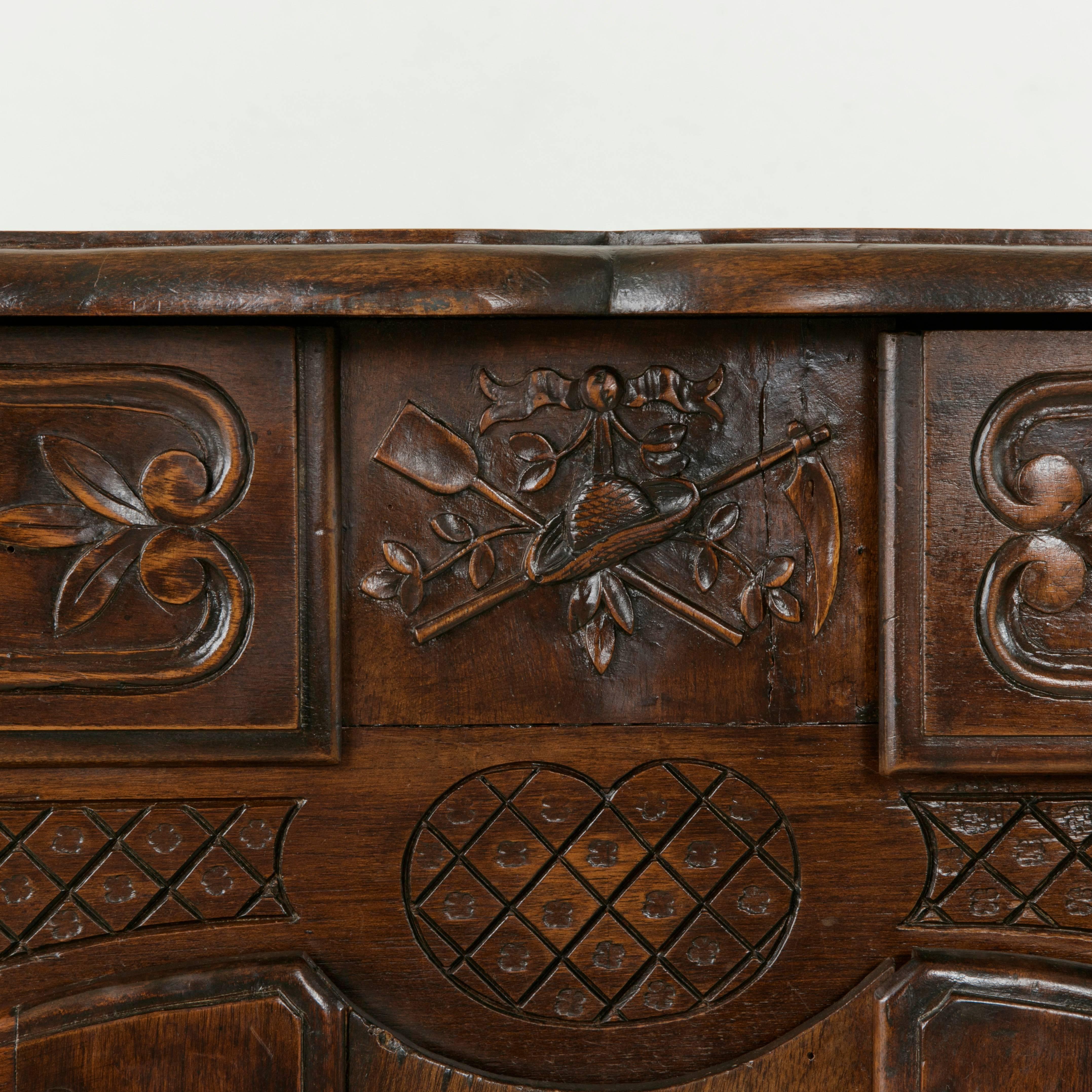 This late 19th century French walnut buffet boasts beautiful hand carvings of garden attributes that include a shovel, scythe, and garden hat, a salute to Provence, the region of its origin in France. Additional carvings of flowers and vines adorn