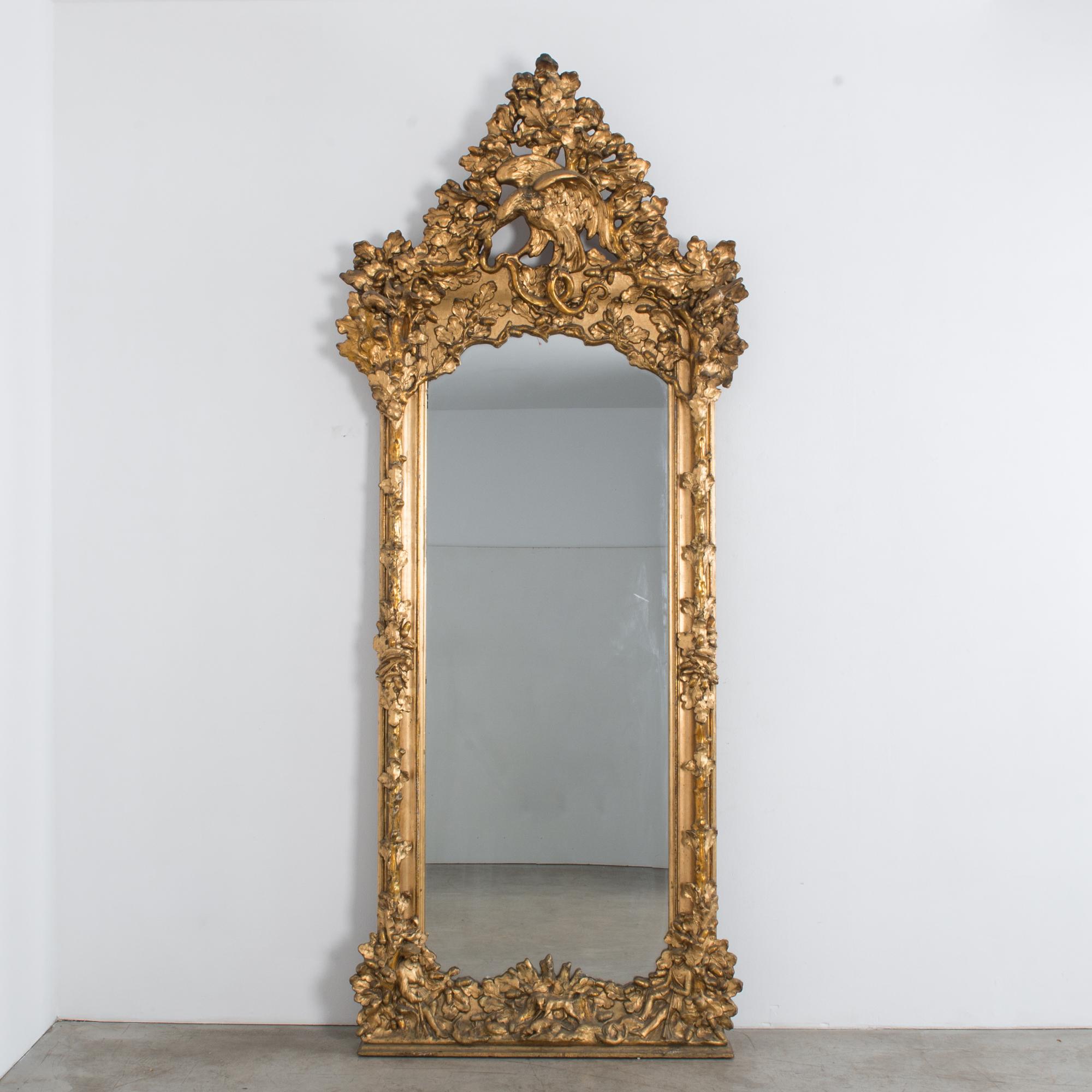 This intricately carved mirror reflects an impressive architectural scale and elaborate imagery, from Austria, circa 1880. Standing over 9 feet tall, this palatial piece will even make an impression in large spaces. A probable family crest, the
