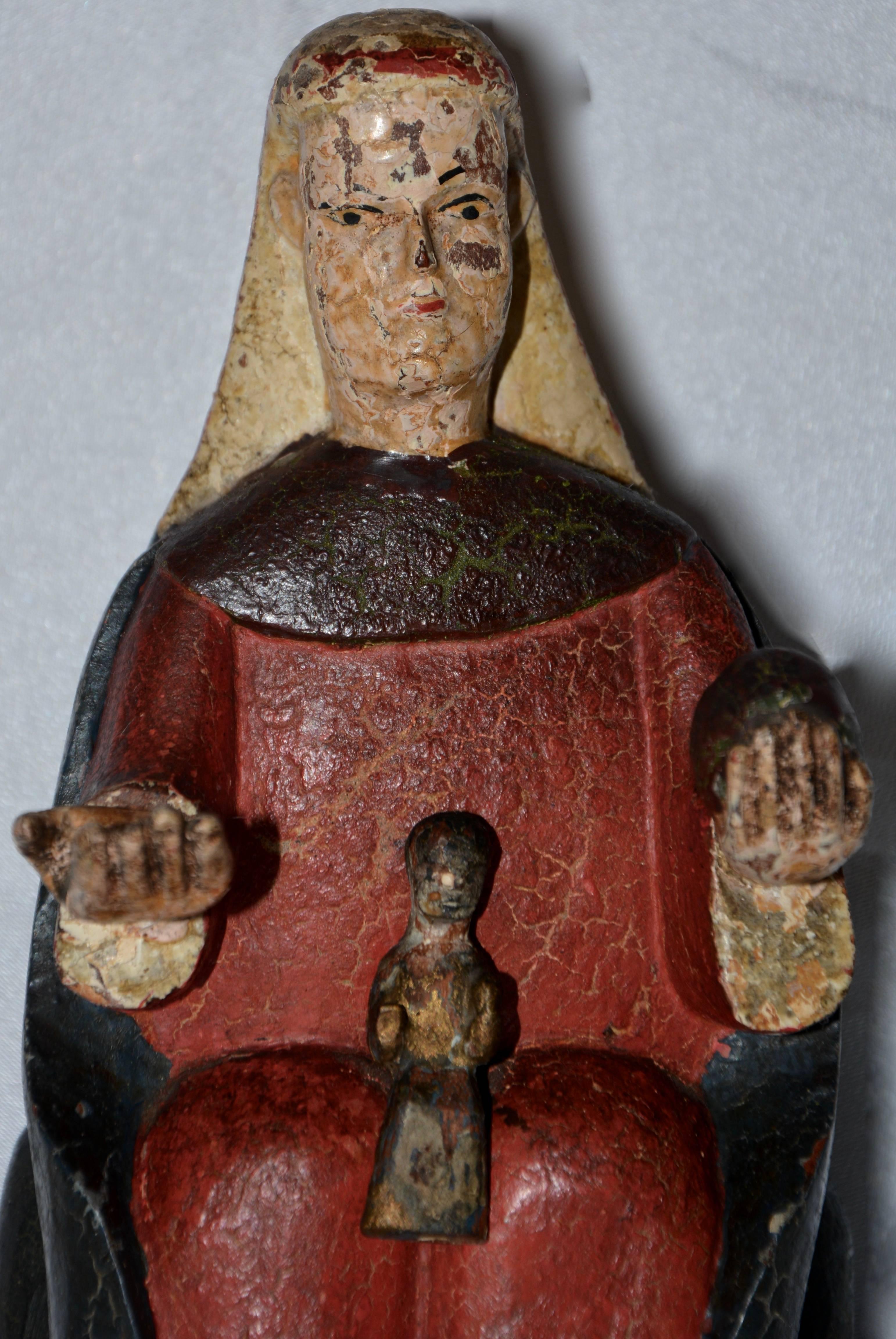 Featured is an antique hand carved polychromed Monserrat Virgin of Catalonia, Spain. The Virgin Mary is depicted seated, dressed in a red gown and dark robe, holding out an open right hand, and holding an orb of the Earth in the left. She has an