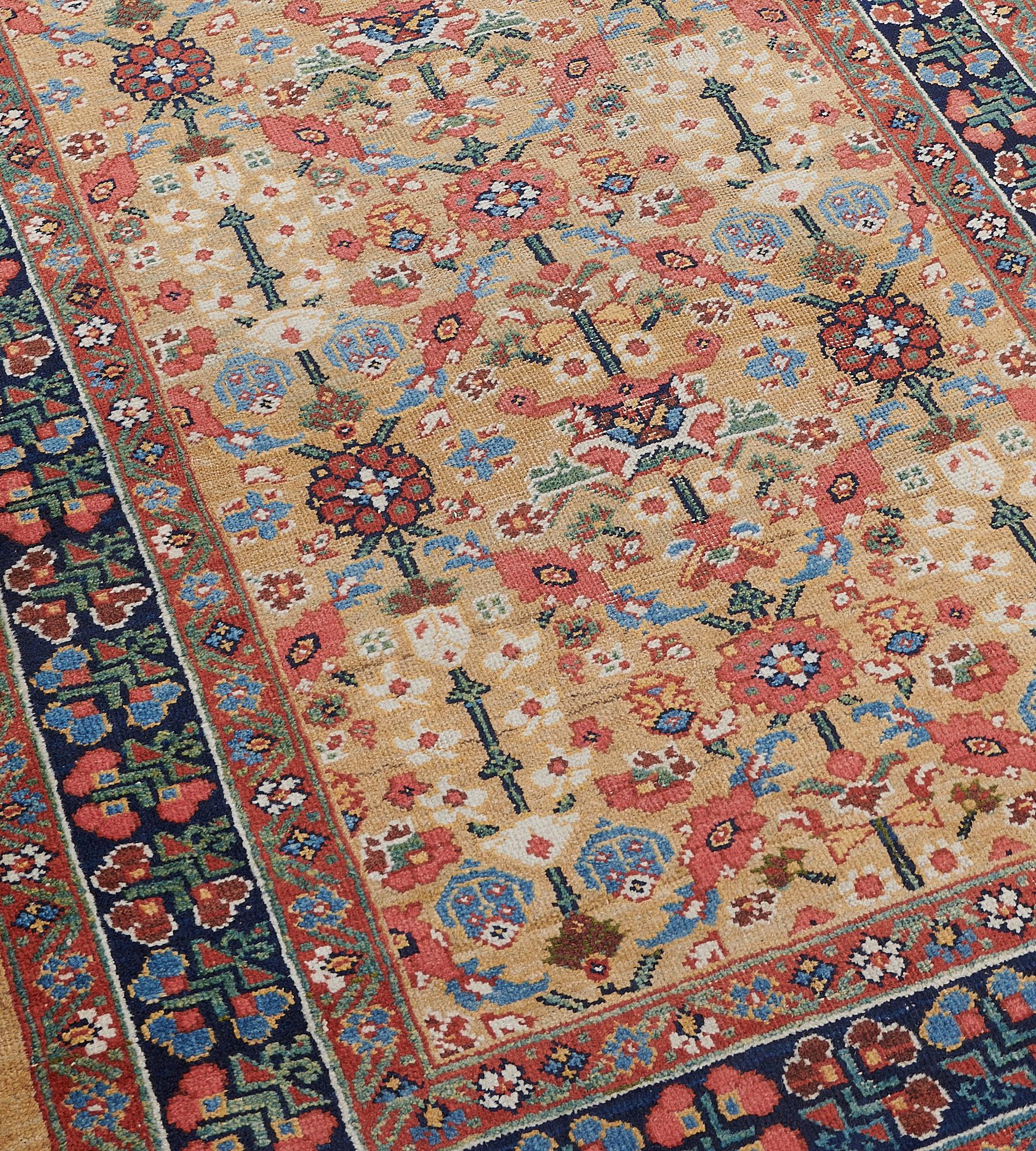 This antique Sultanabad Runner has a camel field with an overall design of terracotta-red, light blue, ivory and green palmette and floral vines scattered with further floral motifs, in a shaded indigo-blue border of light blue, terracotta-red,
