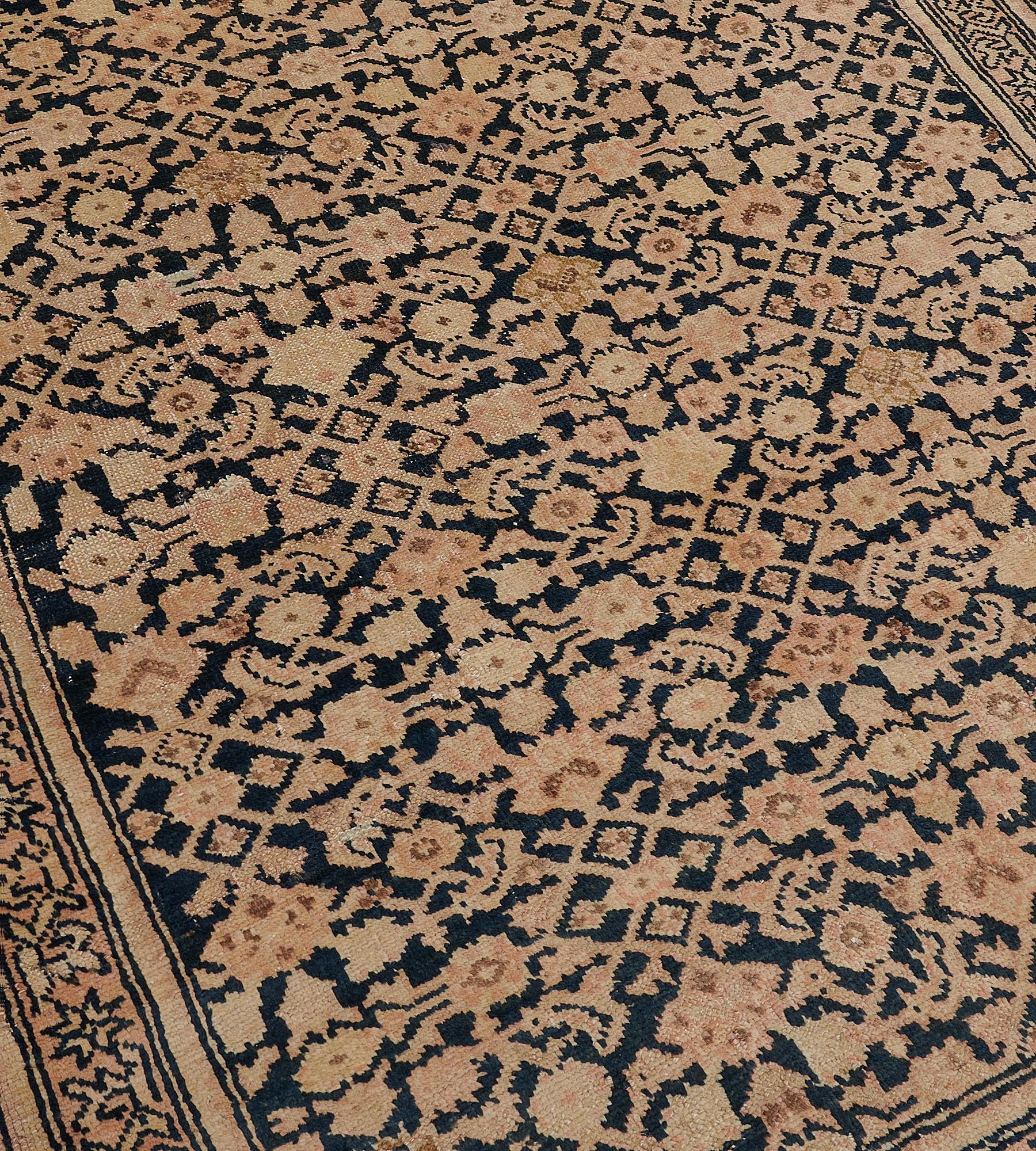 This late 19th century Karabagh runner has a charcoal-blue field with an overall buff-brown herati-pattern, in a soft terracotta-pink border of angular stellar flowerhead vine between plain buff-brown and charcoal-blue minor stripes.