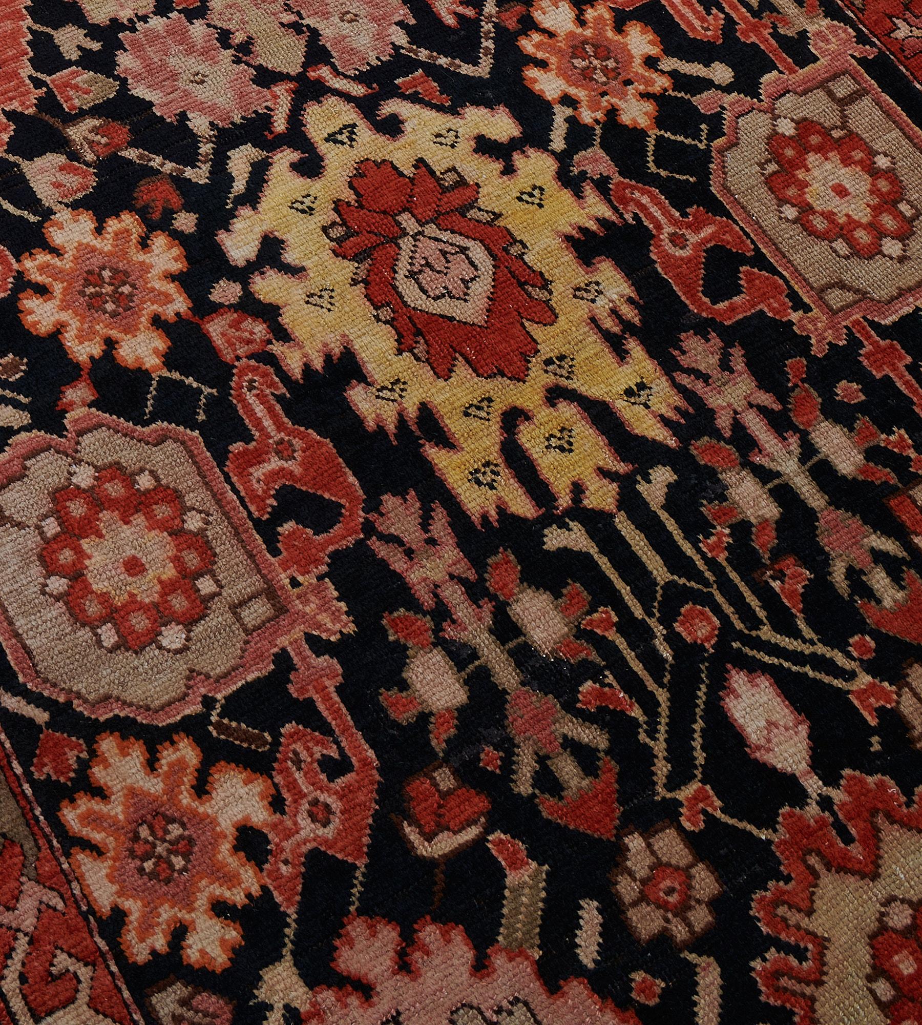 This antique Karabagh runner has a charcoal-blue field with an overall design of bold shaded pink, golden yellow, pistachio-green palmettes linked by angular flowerhead and floral vine, in a terracotta-red angular floral vine border between