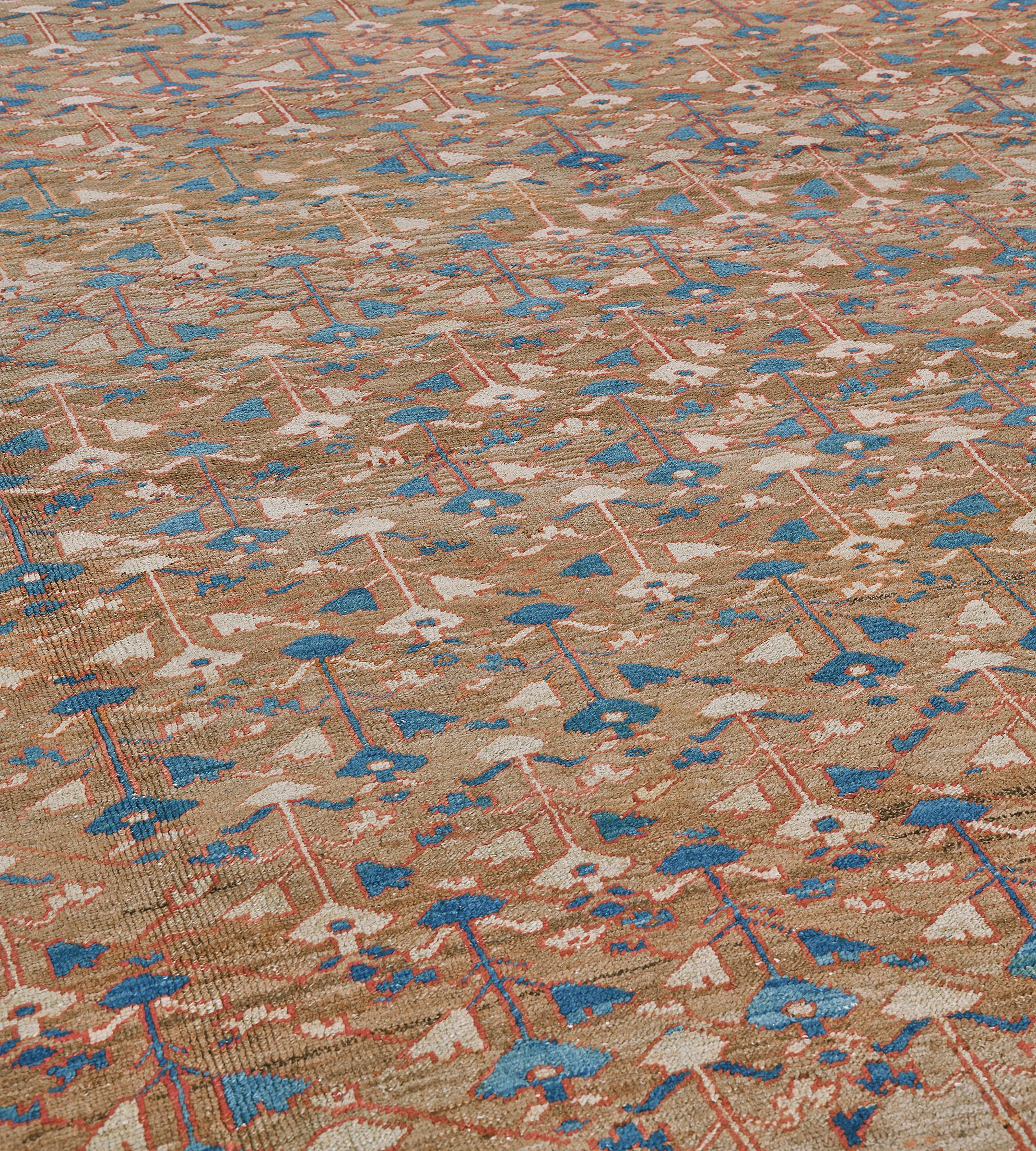 Questo tradizionale tappeto persiano Bakhshaish tessuto a mano in lana presenta un campo generale beige sfumato con steli stilizzati che emettono delicati motivi floreali che formano un'intricata rete di viti, in uno splendido bordo di palmette a