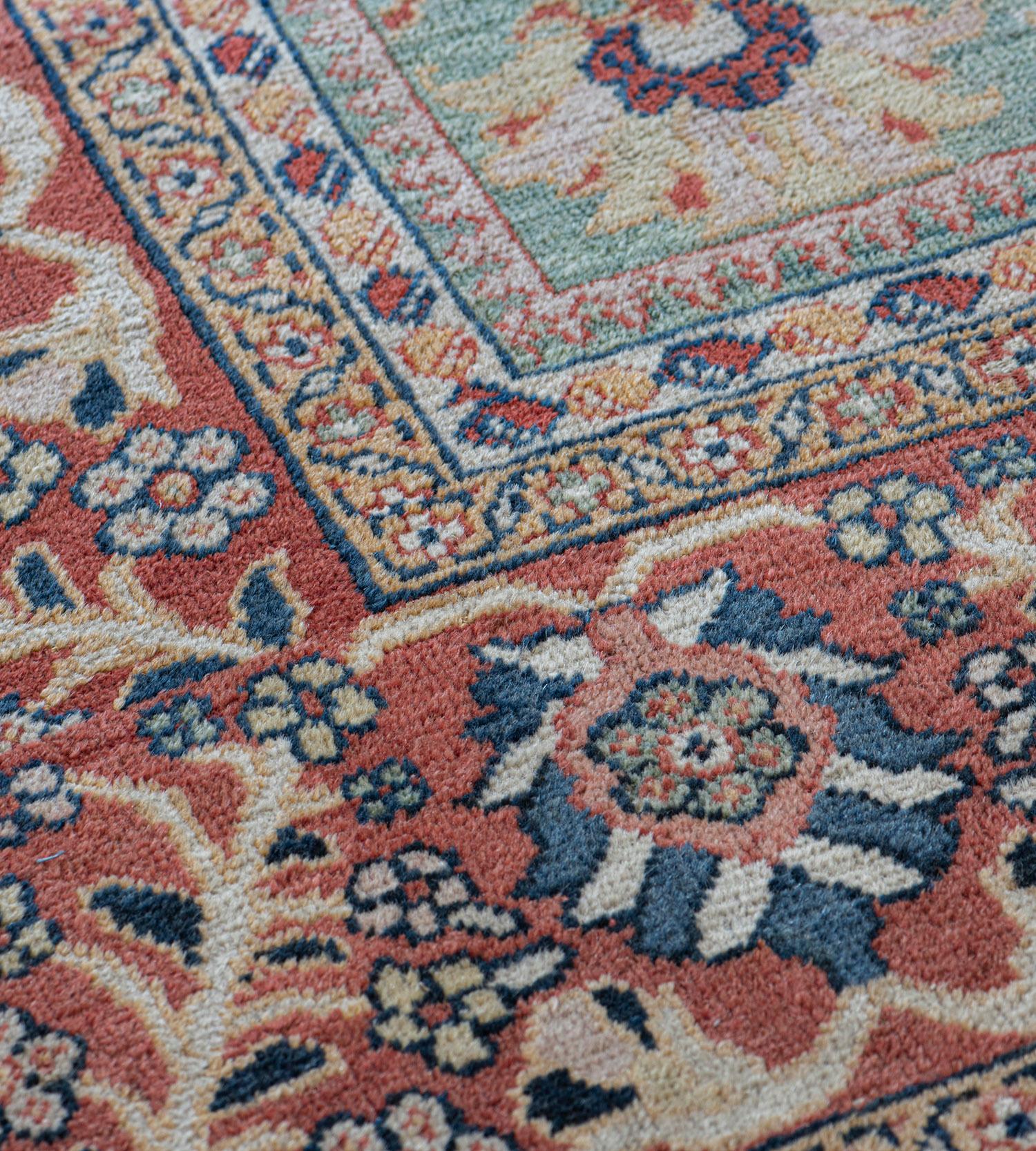 This traditional handwoven Persian Sultanabad rug has a shaded turquoise field with scattered floral motif issued by angled vines and stylized fanned palmettes, in a subtle raspberry-rust scrolling palmette border, between a profusion of floral and