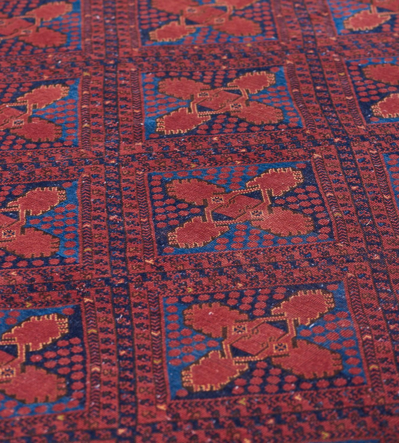 This antique Bokhara rug features a field with diagonal rows of brick-red, shaded blue narrow floral and chevron-pattern stripes around shaded blue and light blue lozenge medallions with a central brick-red X-motif surrounded by brick-red dots, in a