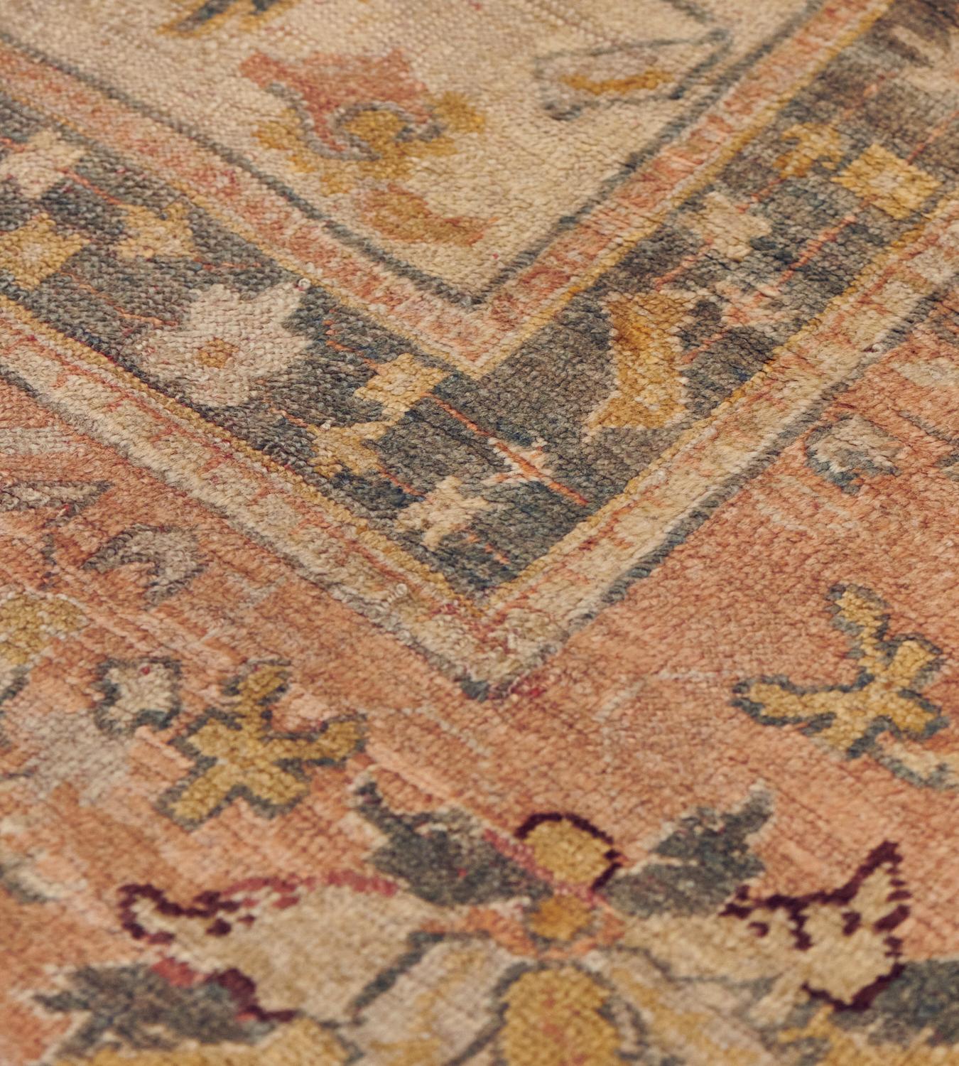 The sandy-yellow field with an overall design of bold palmette vine surrounded by angular floral motifs and serrated leaves, in a broad soft terracotta-red border of ivory and shaded steel-blue palmette vine between steel-blue and ivory floral vine