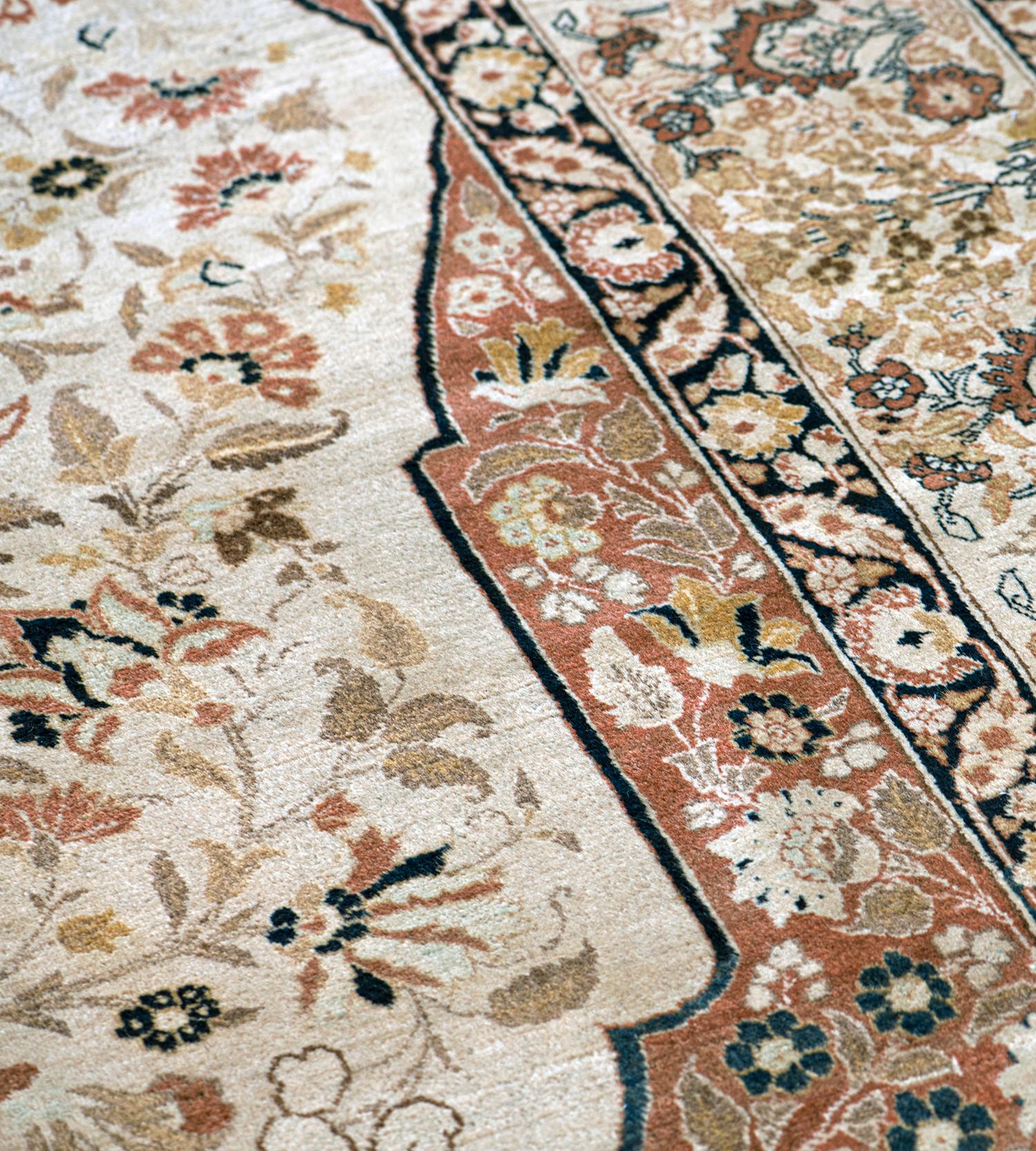 This traditional handwoven Persian Tabriz rug has a soft ivory field of delicate floral sprays, enclosing a majestic rust cusped lozenge medallion of dense flowering motif, with similar ornate spandrels, in an elegant beige border of alternating