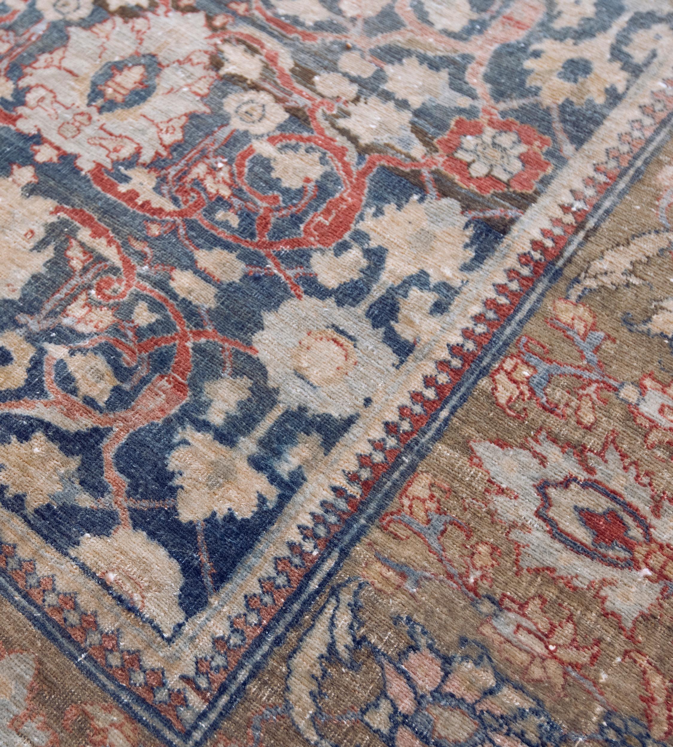 This traditional Tabriz runner has a shaded indigo-field with an overall design of shaded tomato-red vine linking bold light blue and buff-brown palmettes and delicate floral vine stripes, in a broad Khaki-green border of bold polychrome palmettes