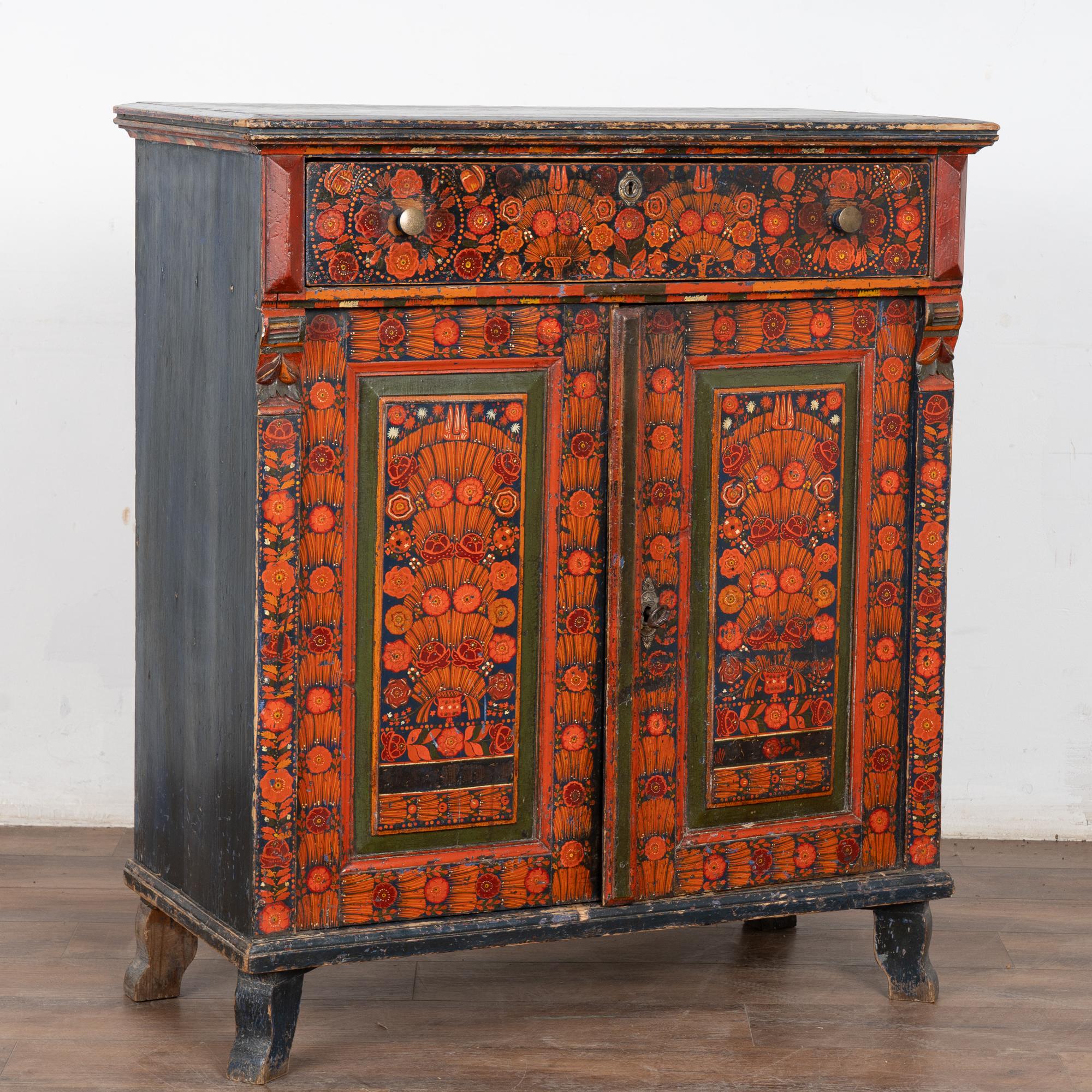 Les couleurs vives abondent dans ce buffet peint original avec des fleurs traditionnelles en rouge et orange sur un fond bleu.
Veuillez prendre un moment pour examiner les photos de près afin d'apprécier les délicieux détails d'art populaire peints