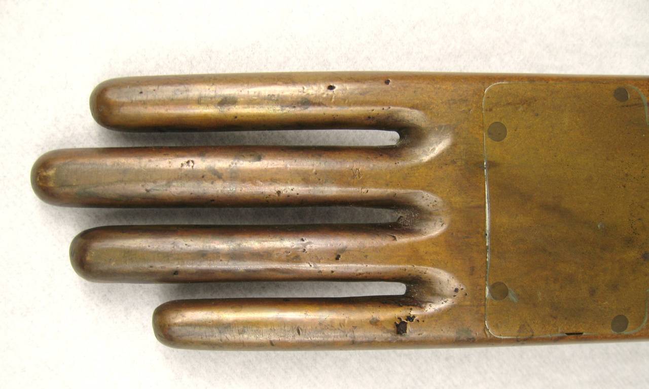 Una mano industriale composta da rame e ottone. Poggia su una base realizzata da qualcuno per tenerlo in piedi. La mano misura 17,25 pollici di H., 3,25 pollici di L., 0,75 pollici di profondità, il supporto misura 26,5 pollici di altezza, la base è