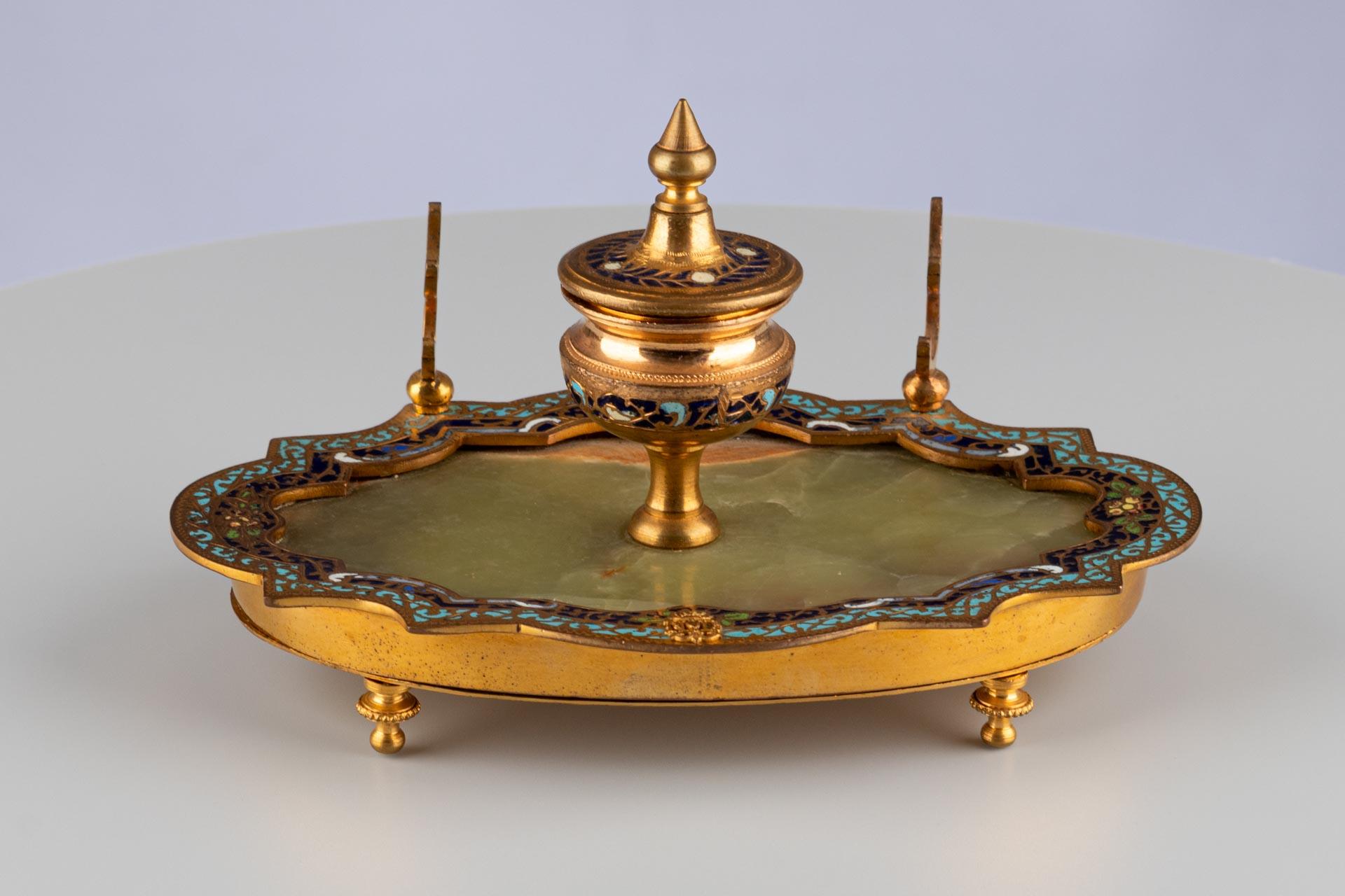 Calamaio con smalto cloisonné e base in onice

Origine: Francia, probabilmente Parigi
Materiale: Bronzo dorato, smalto cloisonné, onice
Data: Circa 1880

Descrizione:
Calamaio ovale con contenitore dell'inchiostro in rilievo al centro, realizzato in