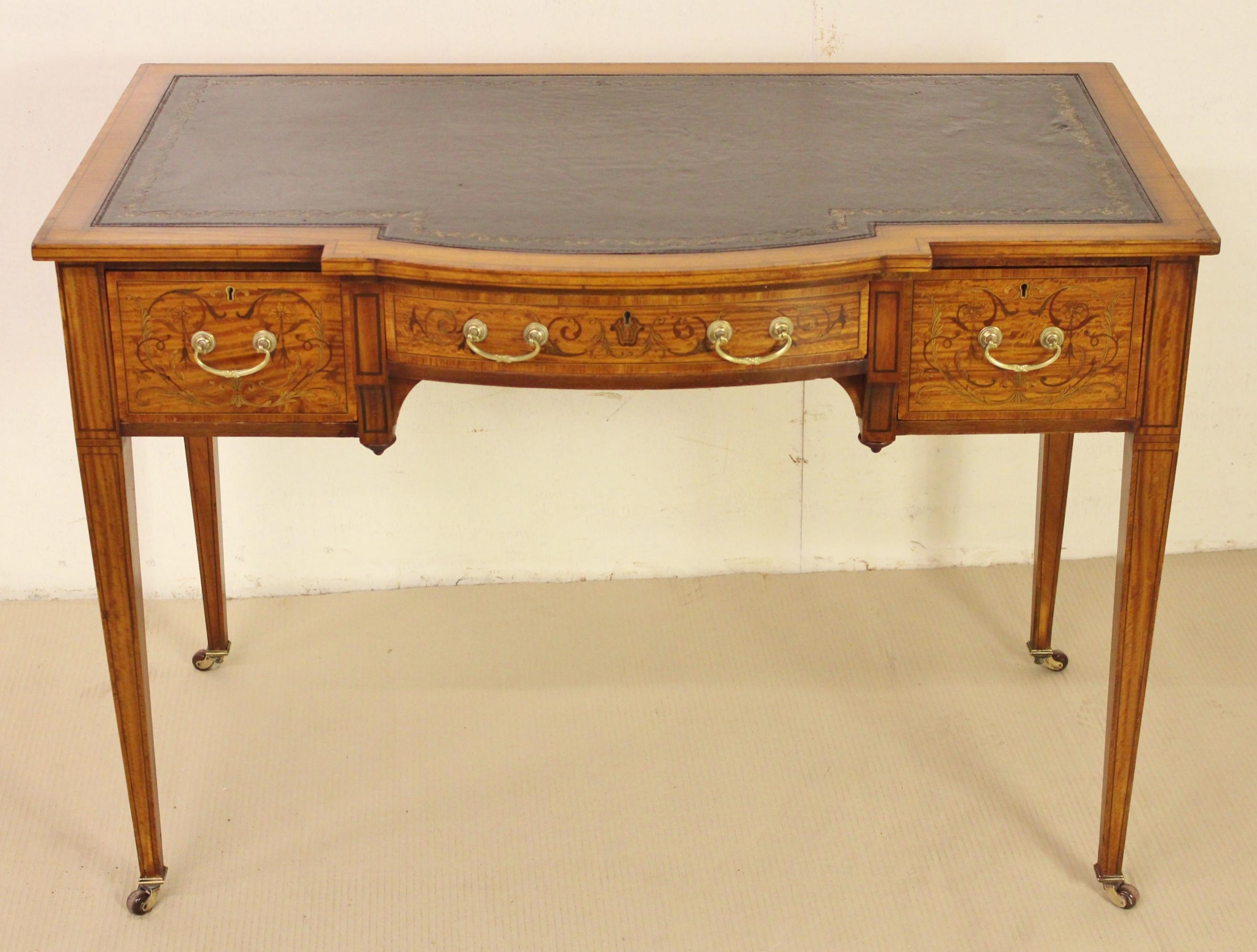 A fine quality inlaid satinwood writing table by the prestigious firm of Maple and Co of London. Dating to the late Victorian period and very well made with stunning satinwood veneers onto a solid mahogany frame. The top and drawer fronts are cross
