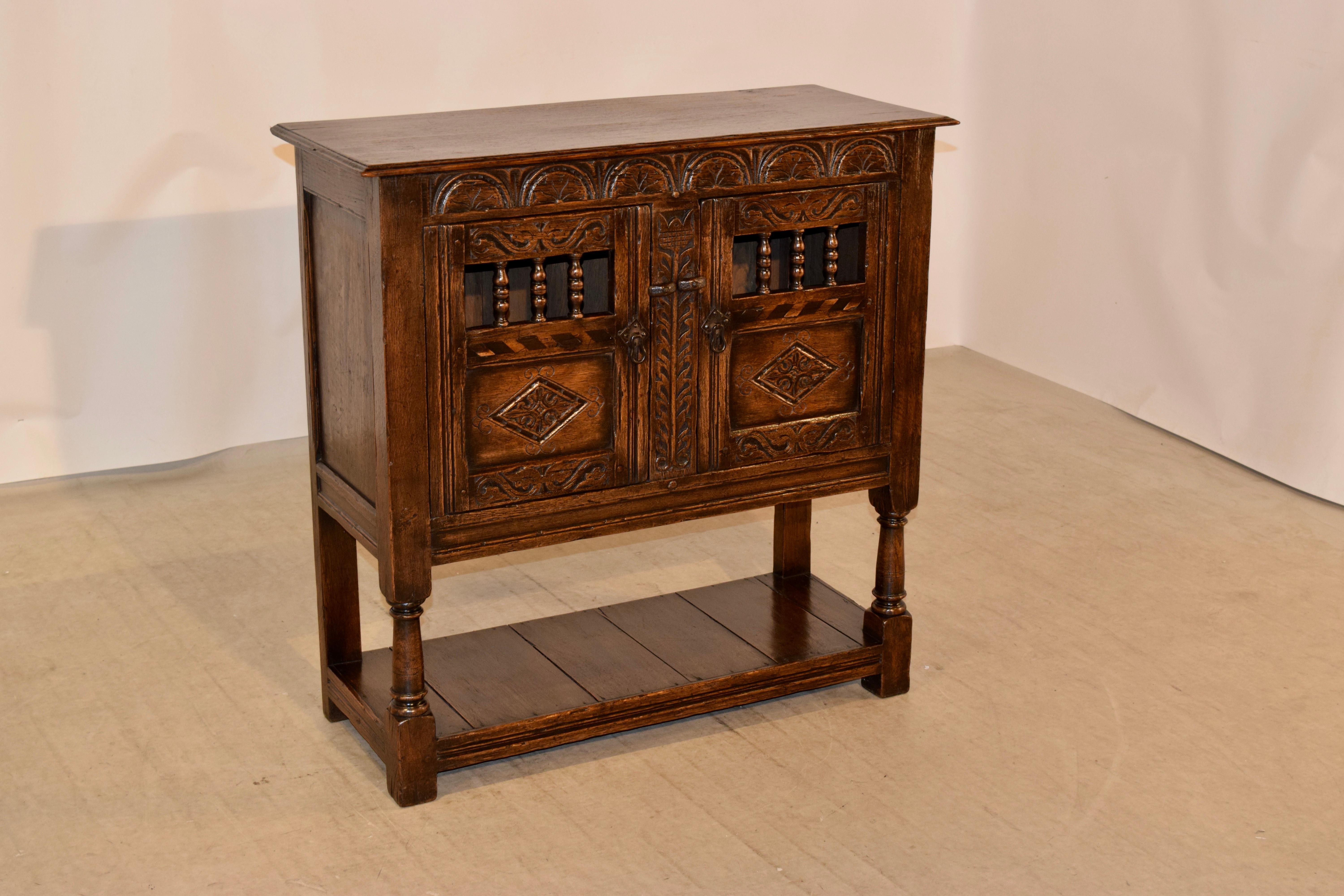 Late 19th century English oak server from the Ipswitch region of England. The top has a beveled edge and follows down to paneled sides and two paneled doors in the front which open to reveal storage. The legs are hand turned in the front and simple