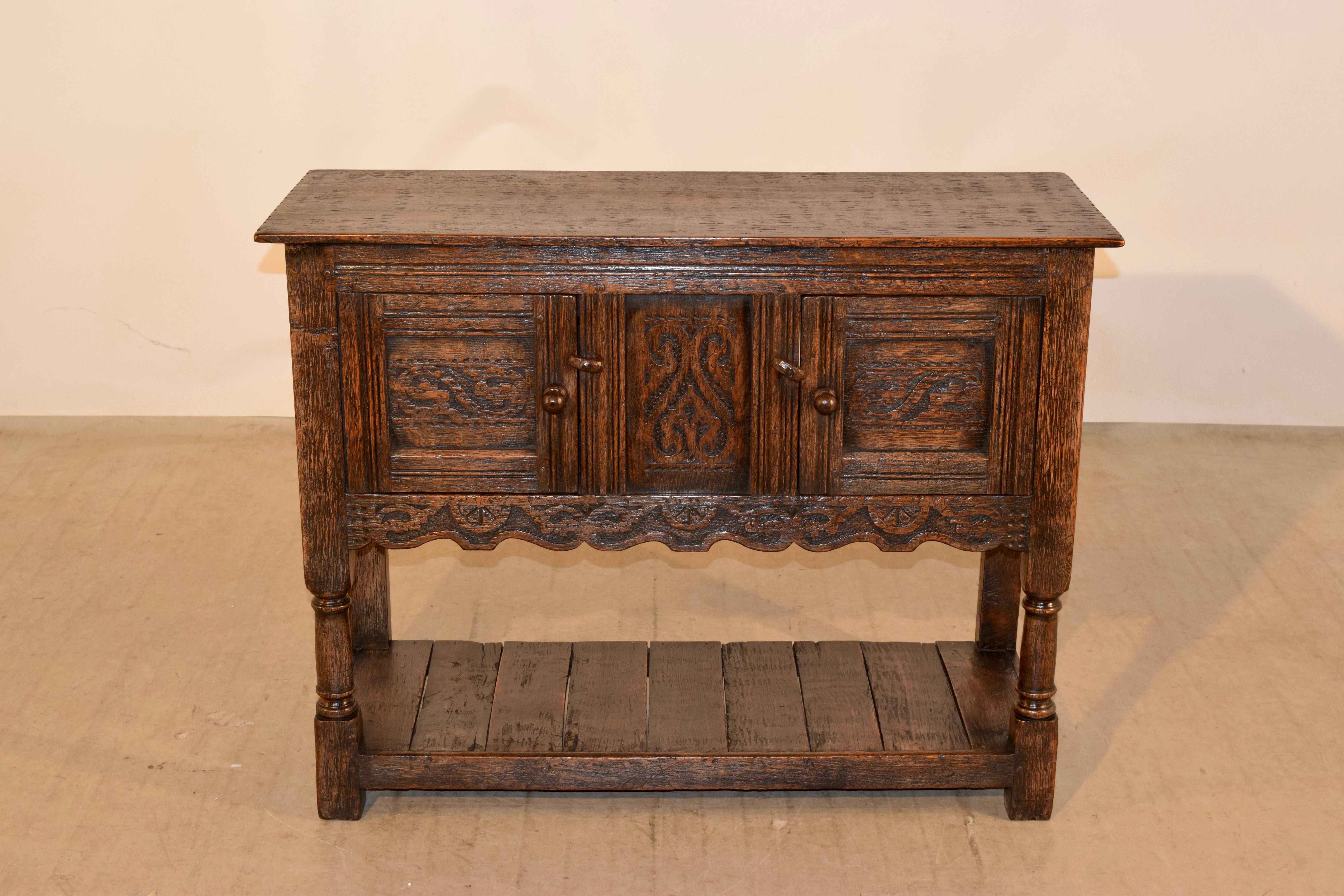 Late 19th century Ipswitch oak server from England. The case contains two single hand carved paneled doors, which open to reveal storage. The case is supported on hand turned legs in the front and simple legs in the back for easy placement against a