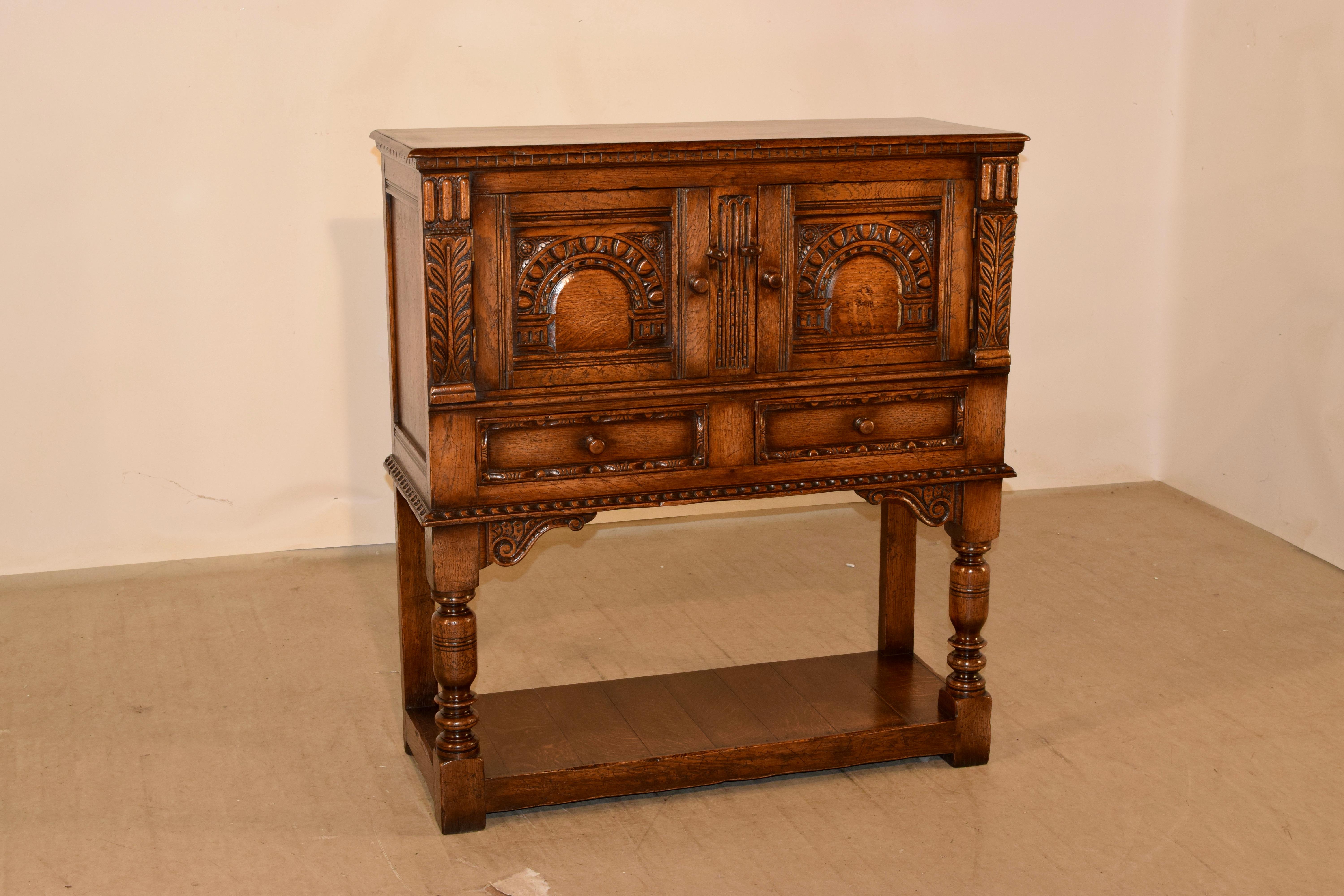 Late 19th century English oak server from the Ipswitch region of England. The top has a beveled edge over a molded edge, and follows down to paneled sides and two paneled doors in the front which open to reveal storage. There are two paneled drawers