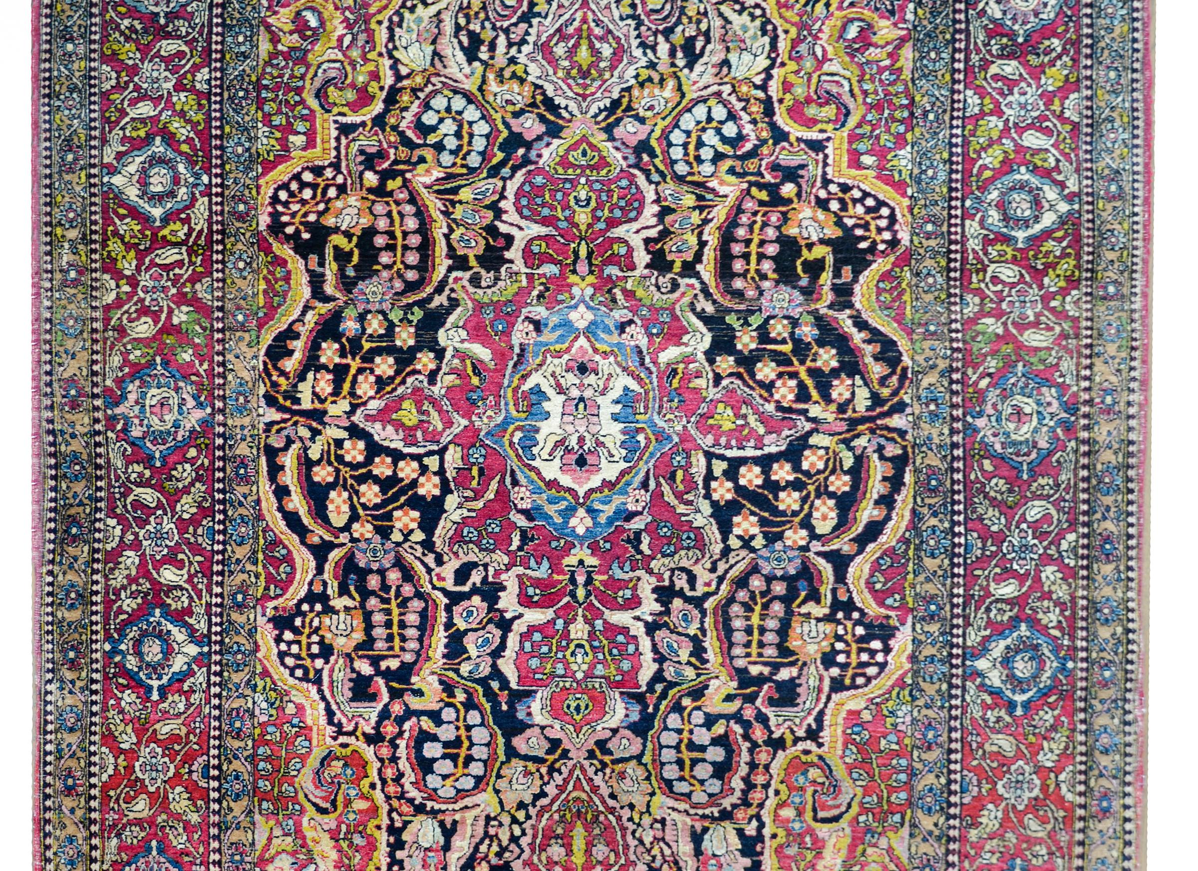 An incredible late 19th century Persian Isfahan rug with a rather large central medallion containing myriad stylized flowers, flowering branches, vines, and leaves, woven in brilliant cranberry, indigo, gold, green, and white colors. The border is