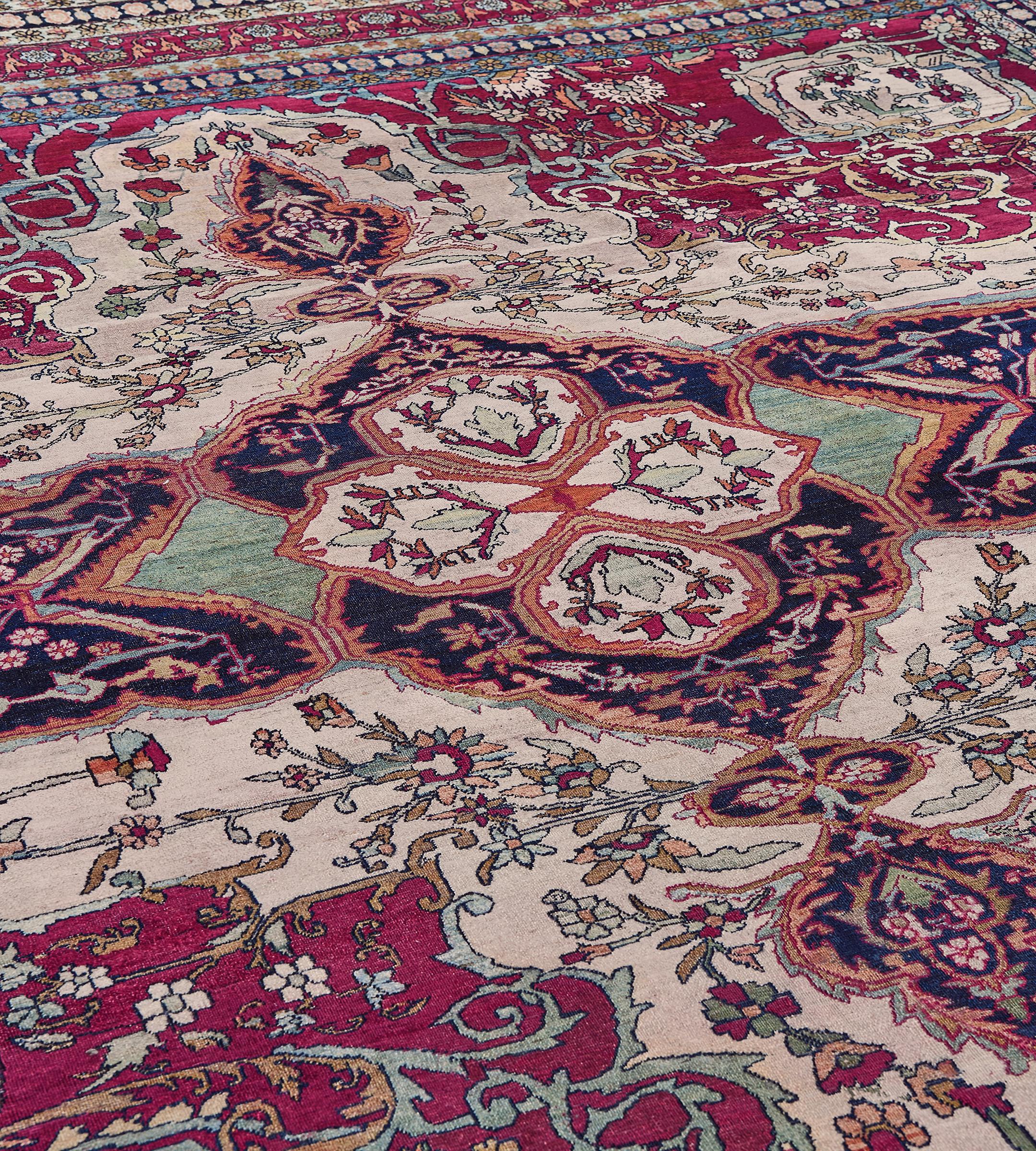 This traditional handwoven Persian Isfahan rug has a refined ivory field of delicate meandering palmette vines, enclosing an imperial indigo arabesque medallion, with shaded royal crimson majestic spandrels, each enclosing scrolling palmette vines,