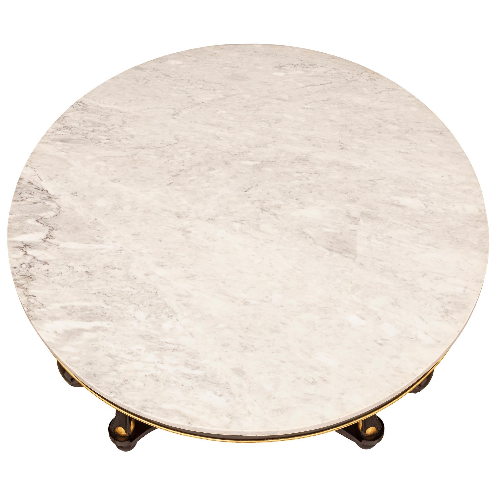 A striking late 19th century Italian ebonized fruitwood and gilt center table with a white Carrara marble top. The circular table is raised by bun feet joined by a triangular serpentine stretcher. Above are three elegant 'S' scrolled swans with