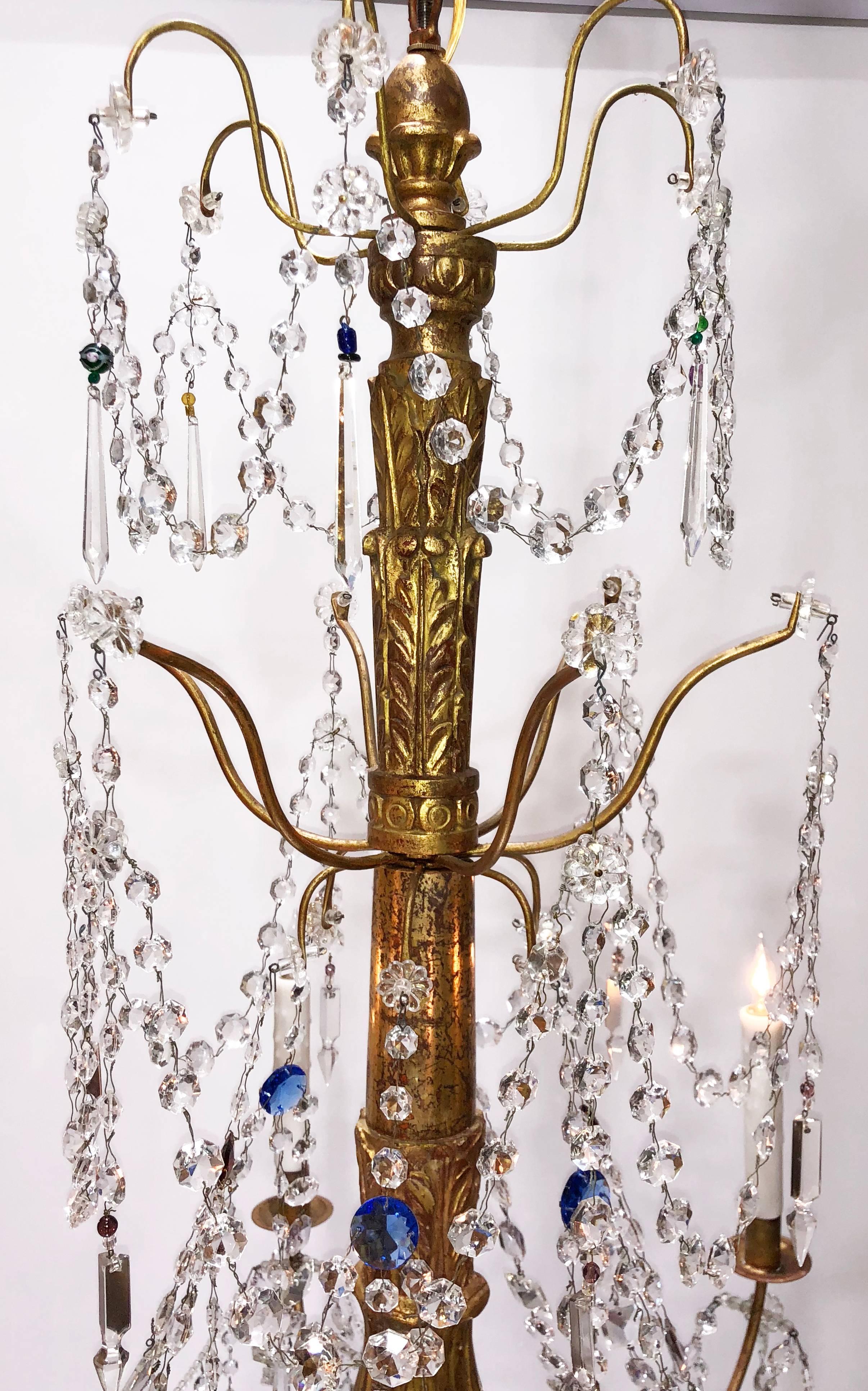 A grand scale Italian Genovese carved giltwood, crystal and tole chandelier, circa 1890, featuring colored crystals. Six-arm chandelier with crystal swag and beading. The chandelier has been recently rewired with new porcelain sockets.