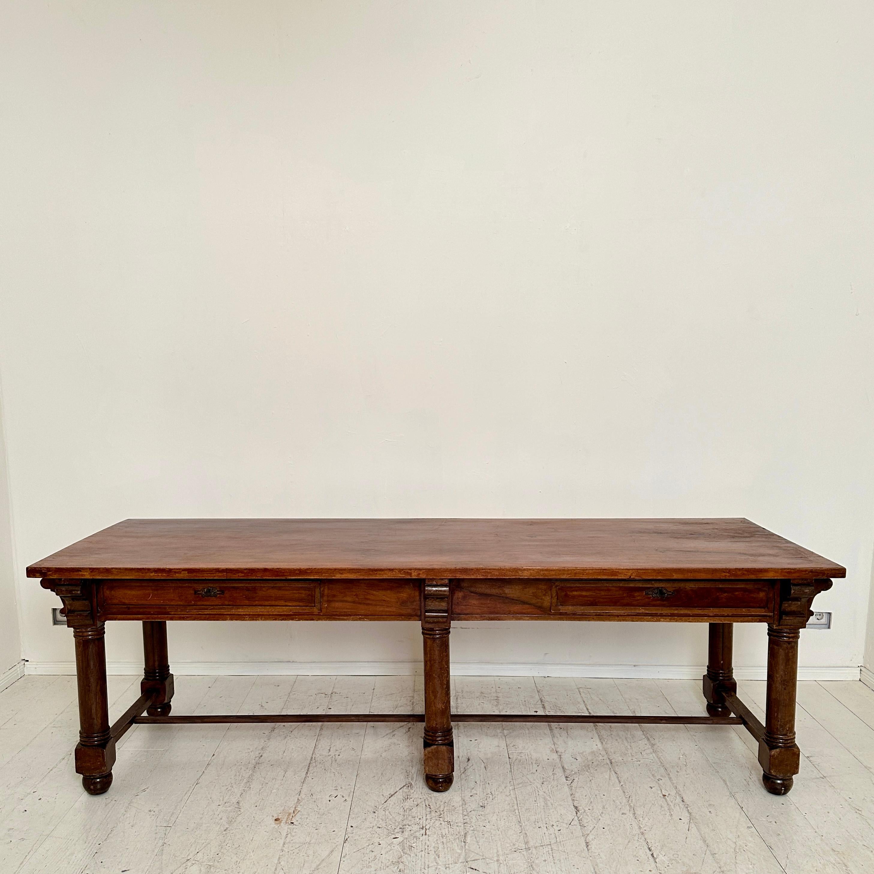 Transport yourself to the opulence of late 19th-century Italy with this exquisite dining table, a splendid relic from 1880. 
The base is crafted from rich brown solid walnut and the table top is veneered in walnut. 
The table emanates a timeless