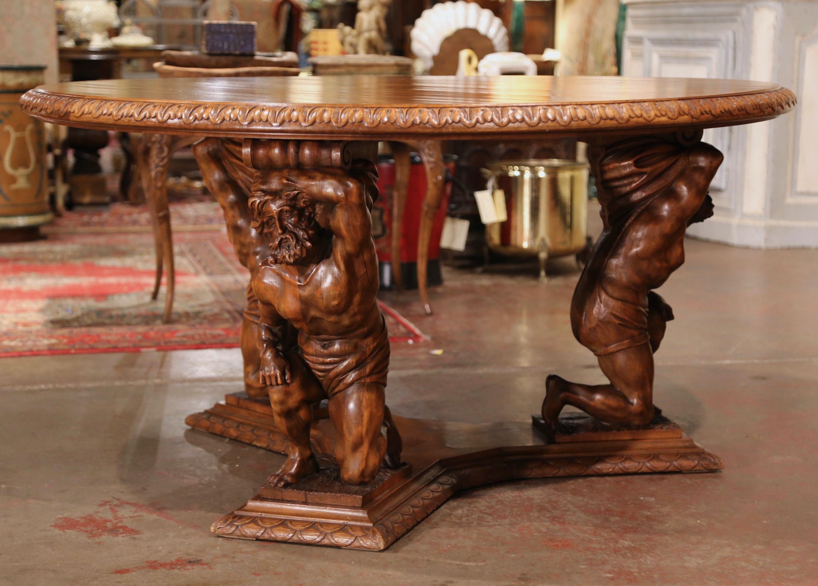 This unusual, sculptural fruitwood table was crafted in Italy, circa 1890. The round center table with a decorative carved edge, features an intricate base with three hand carved Greek men figures resembling Atlas resting on their knees, and