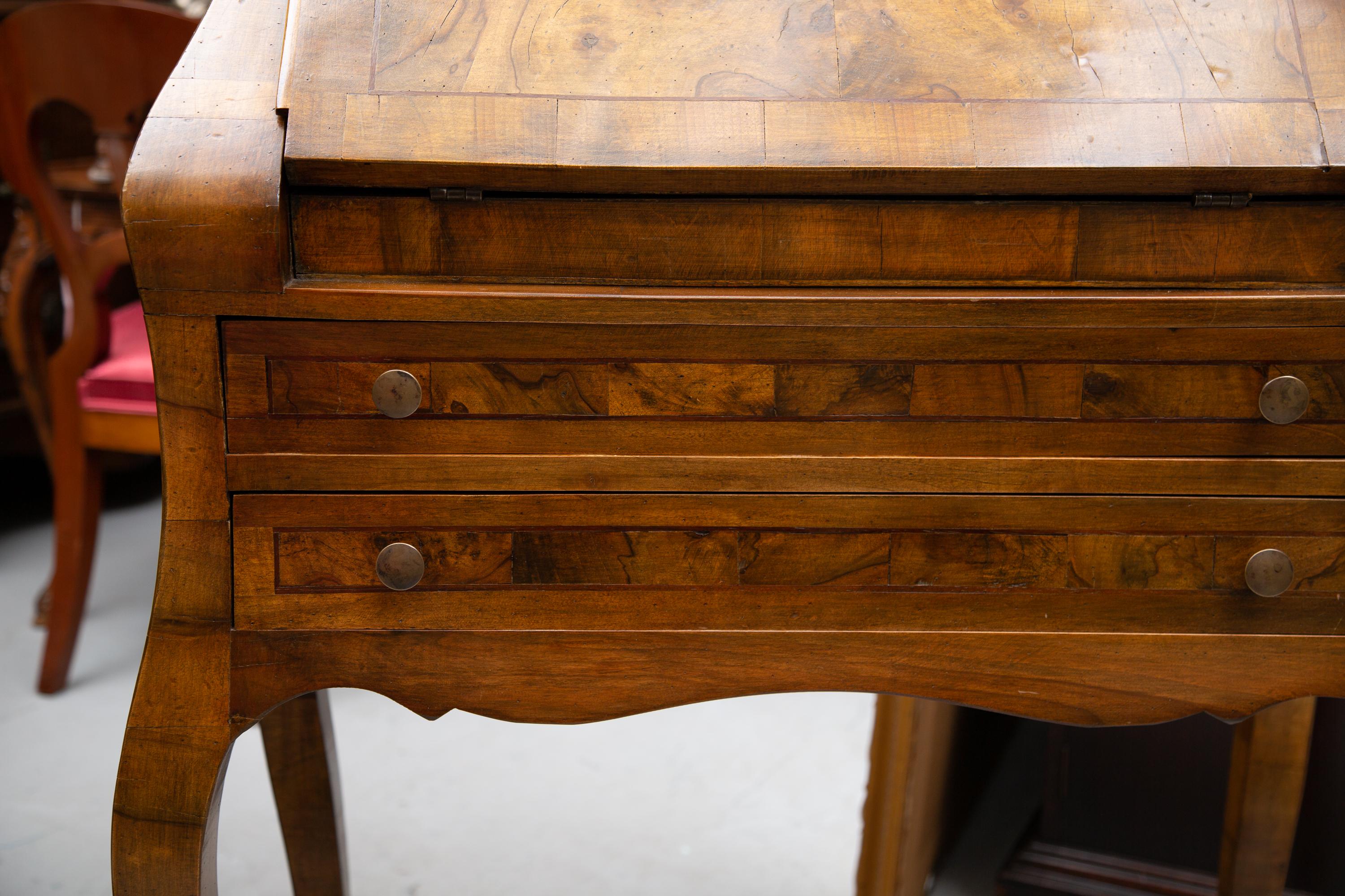This is a mellow Italian burl walnut desk with a drop front top over two long graduated drawers and supported by graceful curved legs, 20th century.