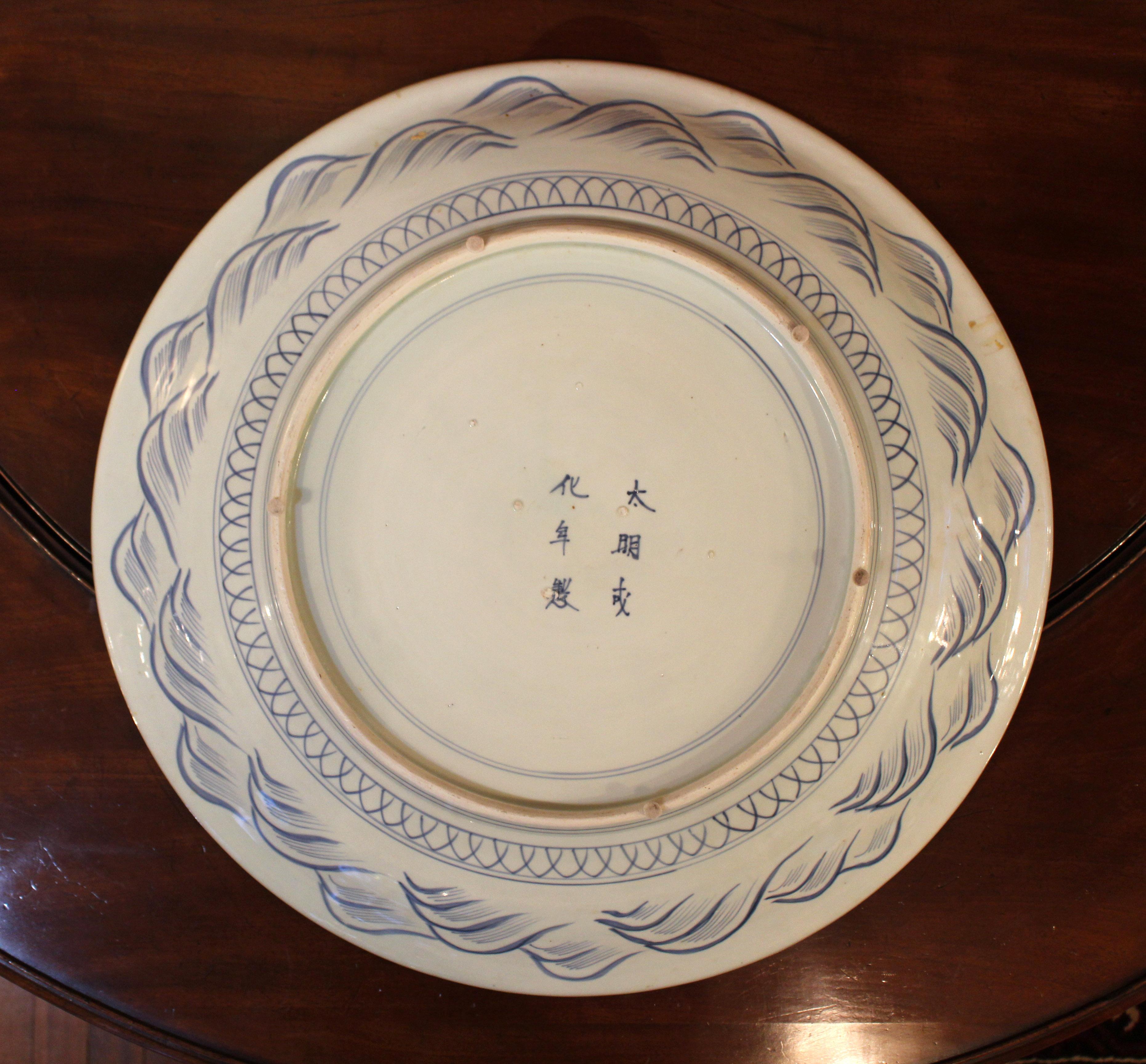 Late 19th century massive scale Arita blue & white charger, Japanese. Pseudo Chinese reign marks. Also called blue & white Imari, as Imari was the export port city. A phoenix oversees a garden filled with chrysanthemums & extensive fish net ground.