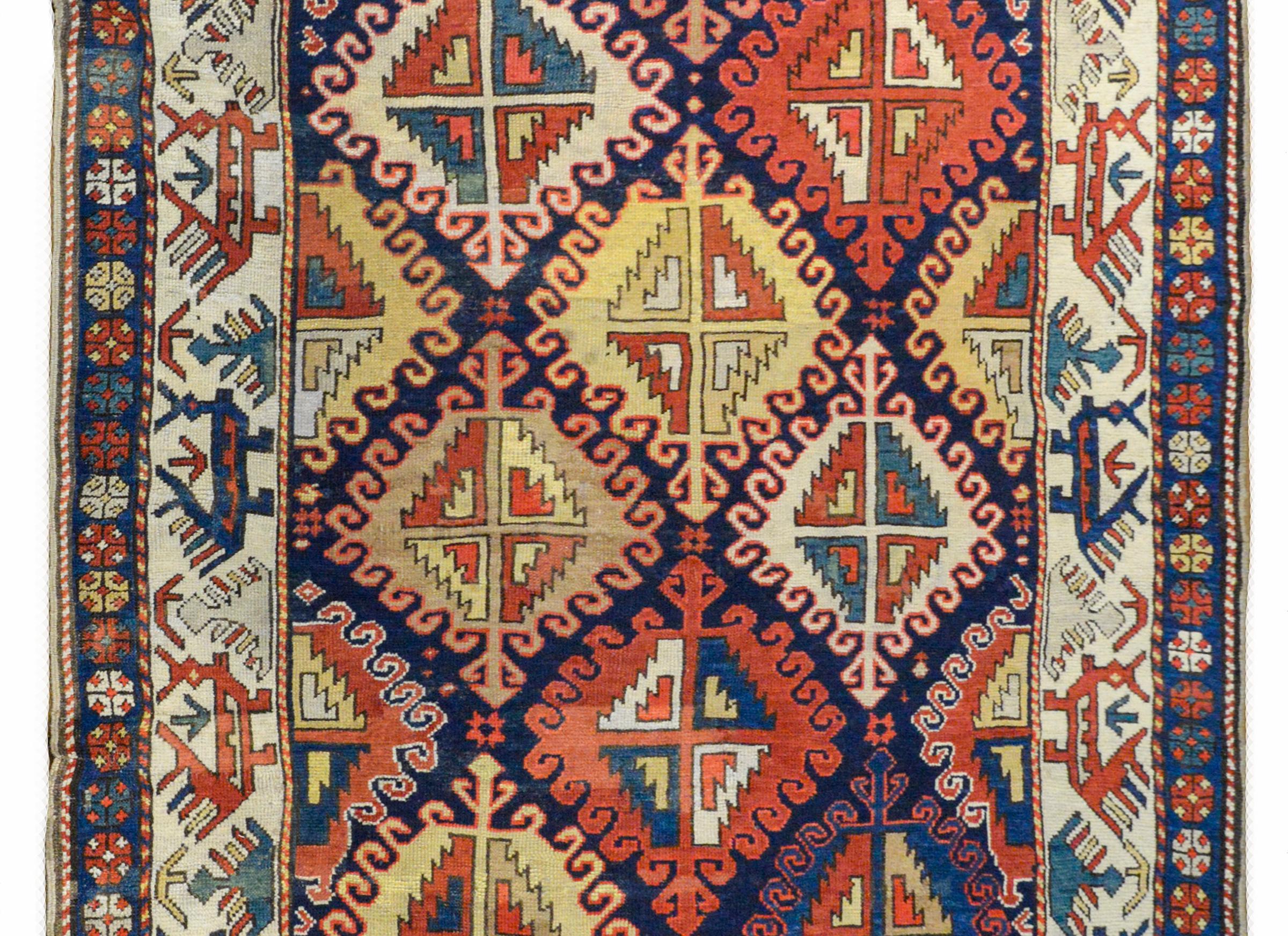 An outstanding late 19th century Kazak rug with the most wonderful bold stylized floral pattern woven in brilliant reds, yellows, greens, and blues, all against a dark indigo background. The border is wonderful with an inner stripe with stylized