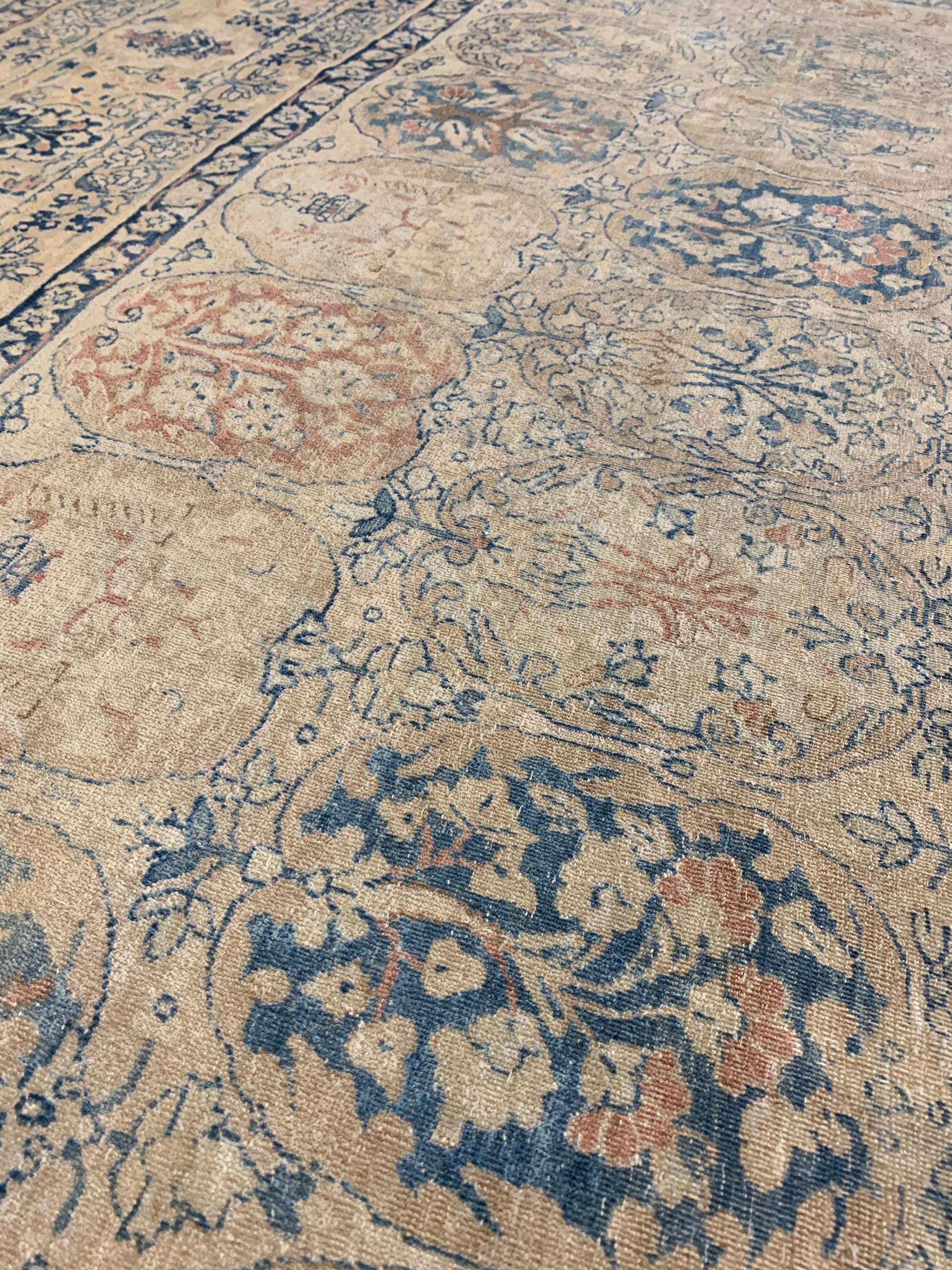 This antique Kerman rug has a central field with an overall design of polychrome linked open lozenges containing a dense profusion of floral vine, in a broad border of polychrome floral cartouche and leafy vine between shady fox-brown and indigo