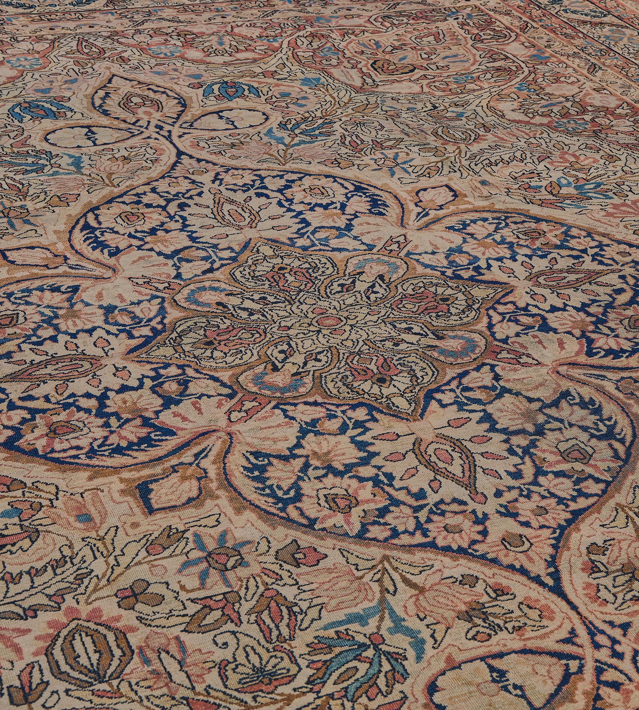 This traditional handwoven Persian Kerman rug has an aged beige field of dense scrolling floral vines enclosing an epic cusped lozenge medallion, in an ornate scrolling floral vine border, between further rustic floral stripes. Signed by its master