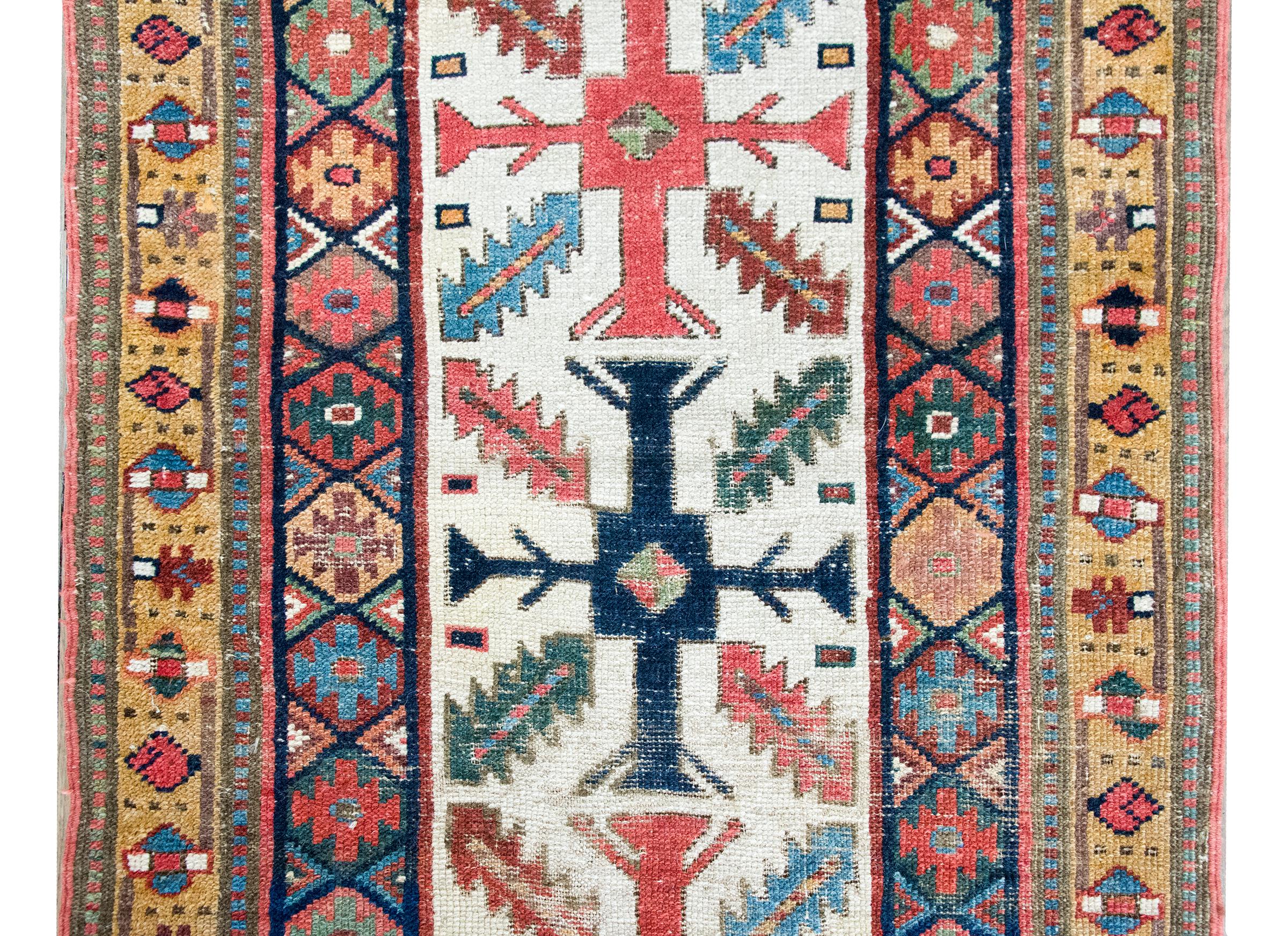 Una icónica alfombra Kuba de Azerbaiyán de finales del siglo XIX, tejida a mano en lana ricamente teñida, con un fascinante campo central de hojas estilizadas repetidas que apuntan hacia pequeñas cruces flotantes; cada motivo varía ligeramente, como
