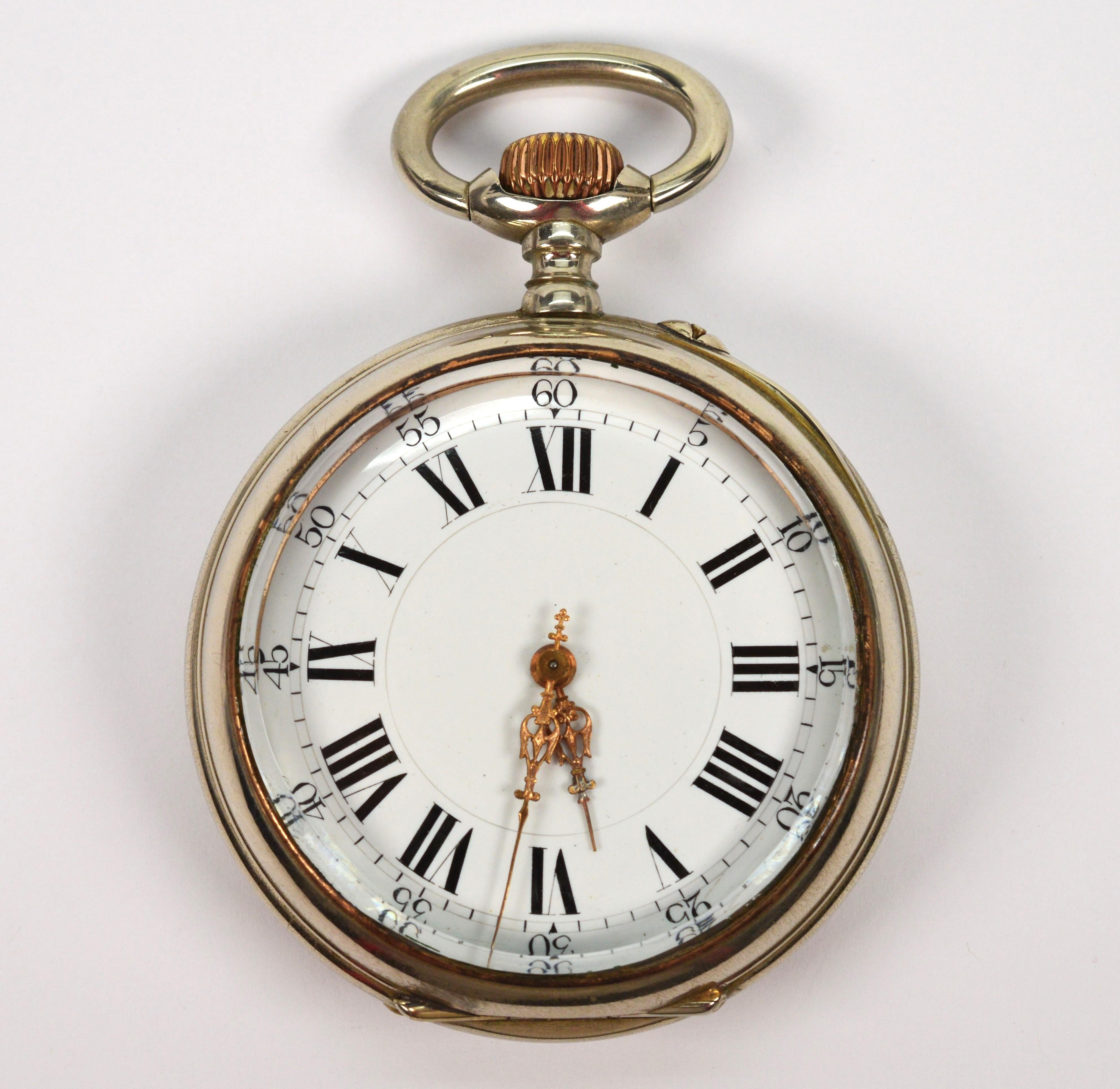 Cased in nickel, this hefty desk-size 70mm pocket watch is certainly impressive. With a bright brass crown, this large robust palm-size  2-5/8 inch round pocket watch has a nickel outer back case #607954 and a open front crystal display. It's