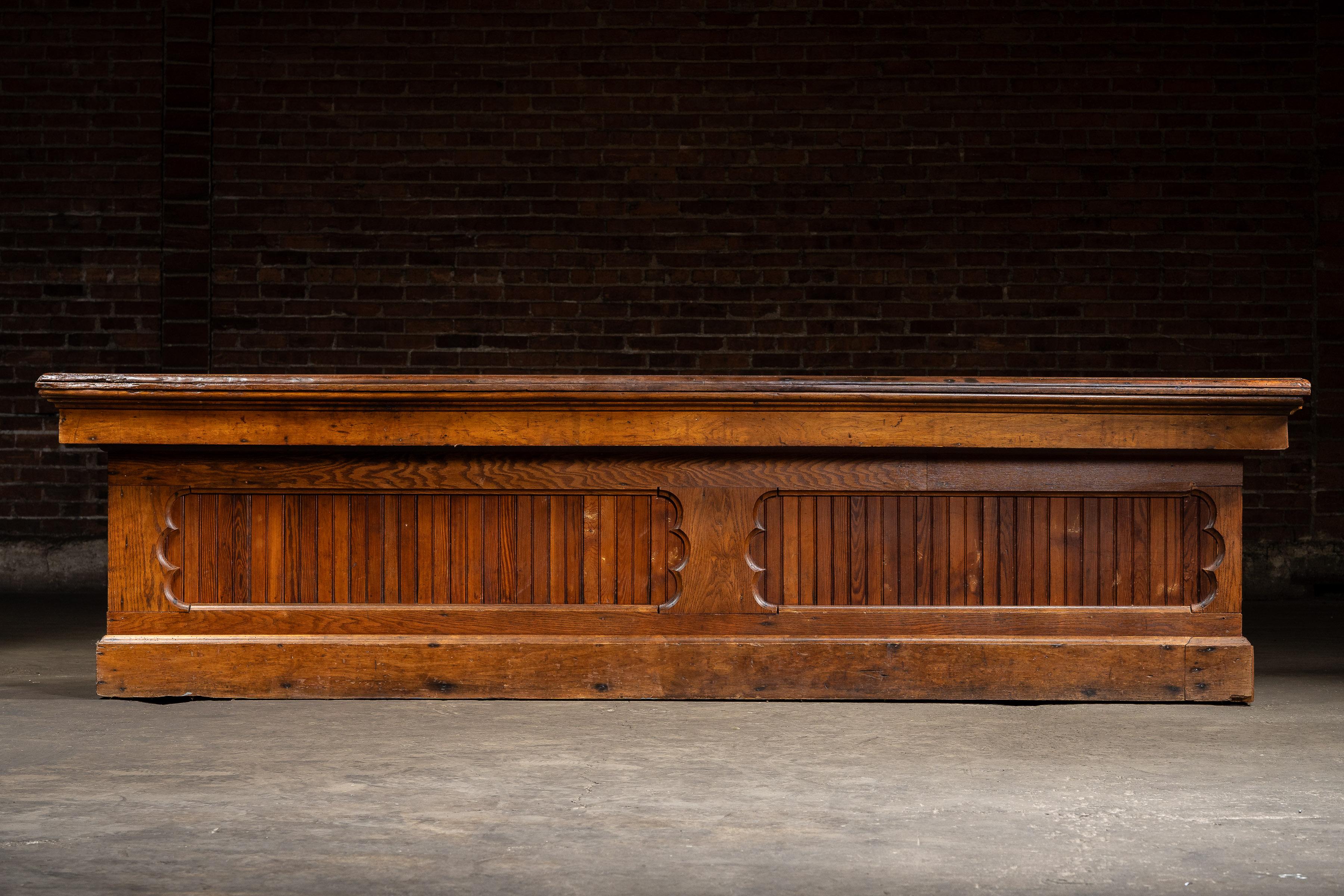 Ce comptoir à grande échelle a été construit à l'origine pour un mercantile ou un magasin général, conçu avec de multiples tiroirs pour un stockage efficace et une utilisation quotidienne. La pièce est construite en pin massif avec des panneaux