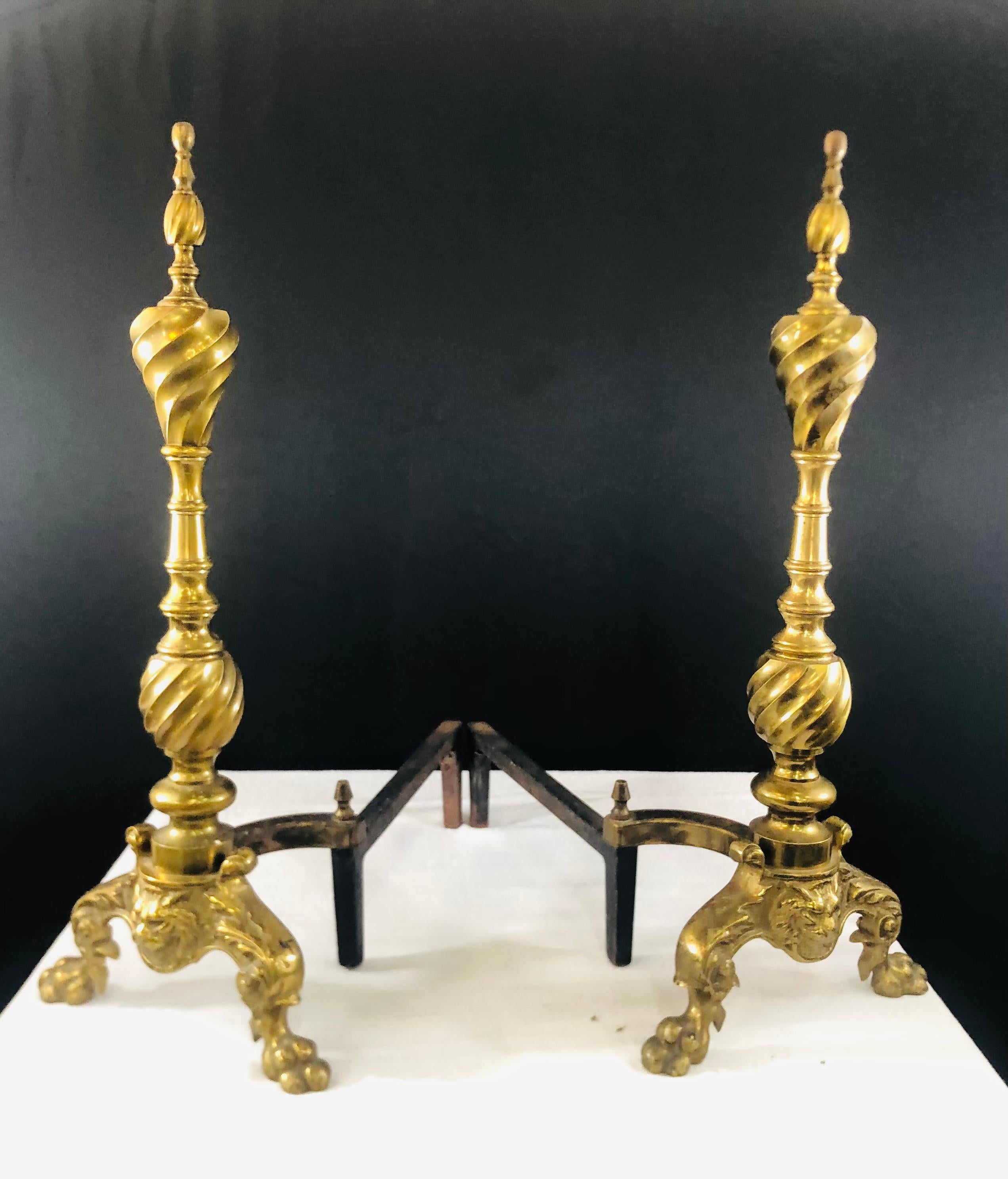 A classy pair of brass English andirons. Each andiron sets on paw shaped feet and features elegant carving brass twisted design on the columns. The andiron is almost 2 feet high and will add style and sophistication living room and make your