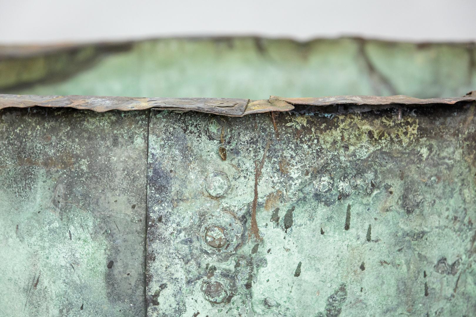 Large scale naturally verdigris English riveted copper. Wonderful colour throughout. Some minor blemishes top the rim and exterior, perfectly solid and sturdy for use as a planter or log bin. Holes drilled for drainage. England circa