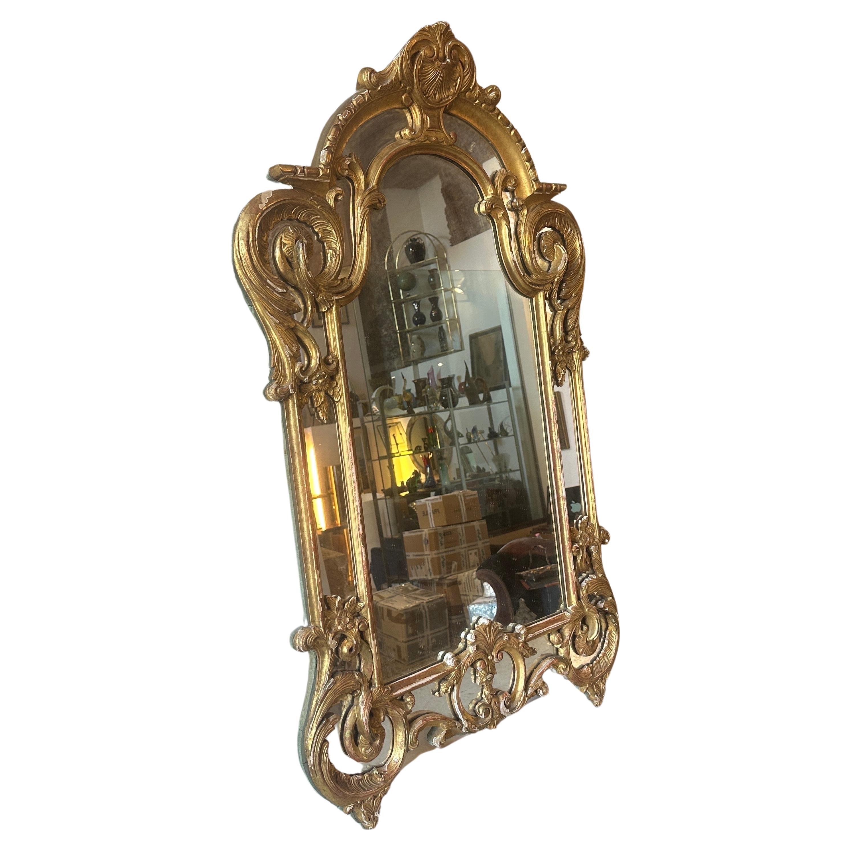 This gilded wood Italian wall mirror is a beautiful and elegant piece of decorative art and furniture from late 19th century. The Louis Philippe style, which was popular during the period, is known for its simplicity, grace, and understated