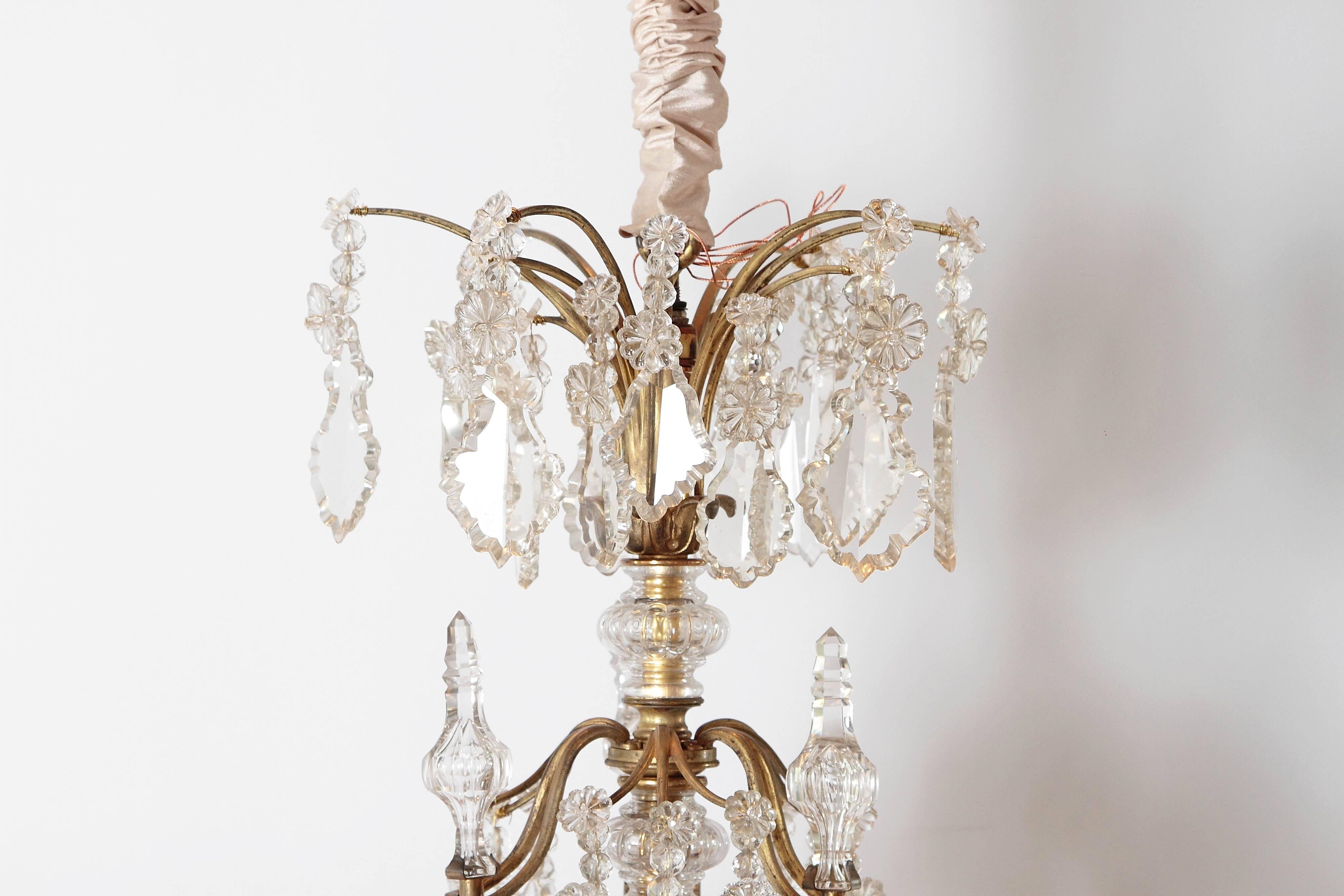 A Louis XV style crystal chandelier with central crystal clad stem and gilt bronze arms with crystal swags and drops, late 19th century, France.