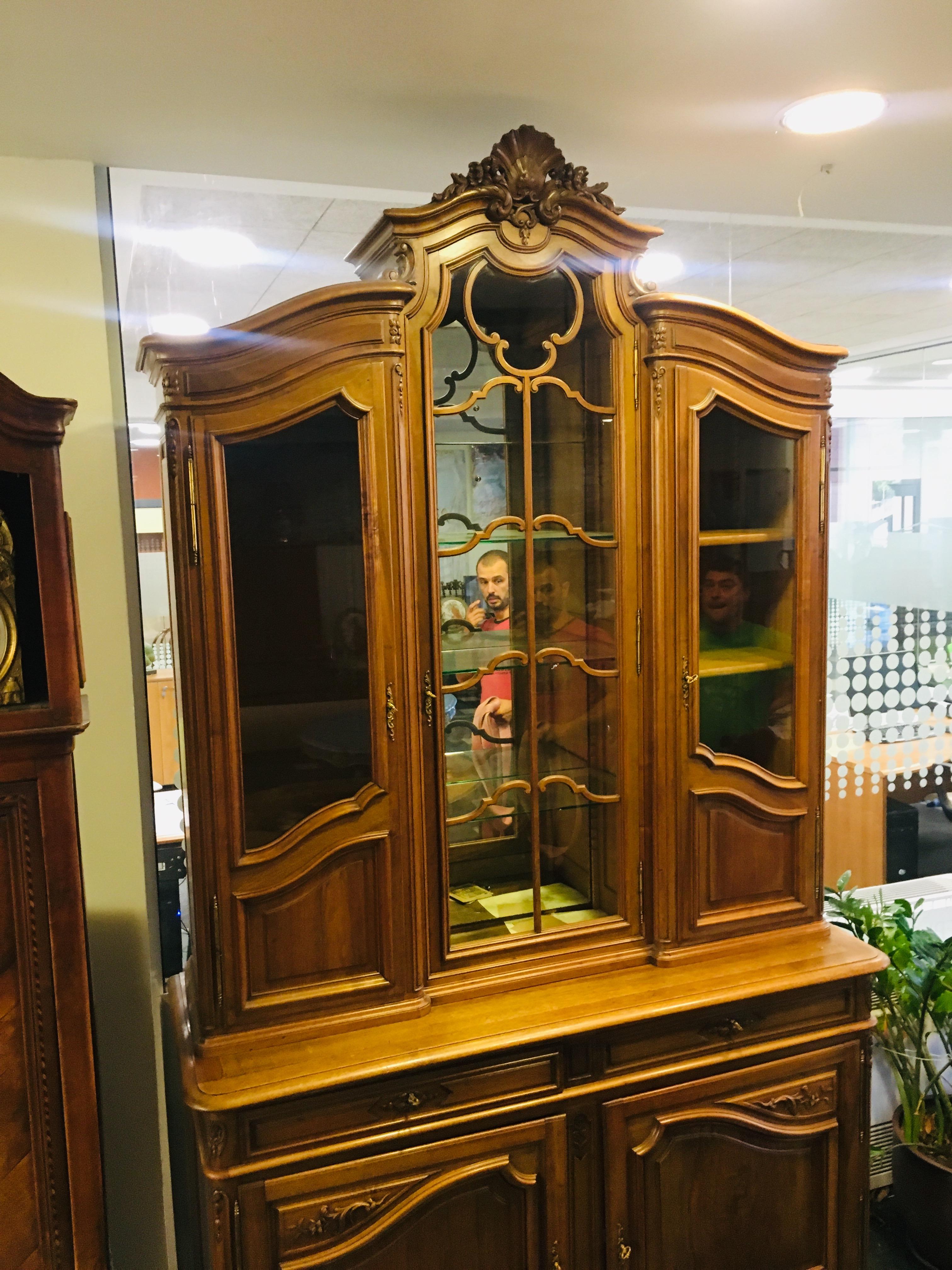 A late 19th century Louis XV style French vitrine a deux corps made of solid walnut with raised panels and beautiful carved details. Crown has curved corners with floral carving at the center. Buffet provides perfect storage place, with top part
