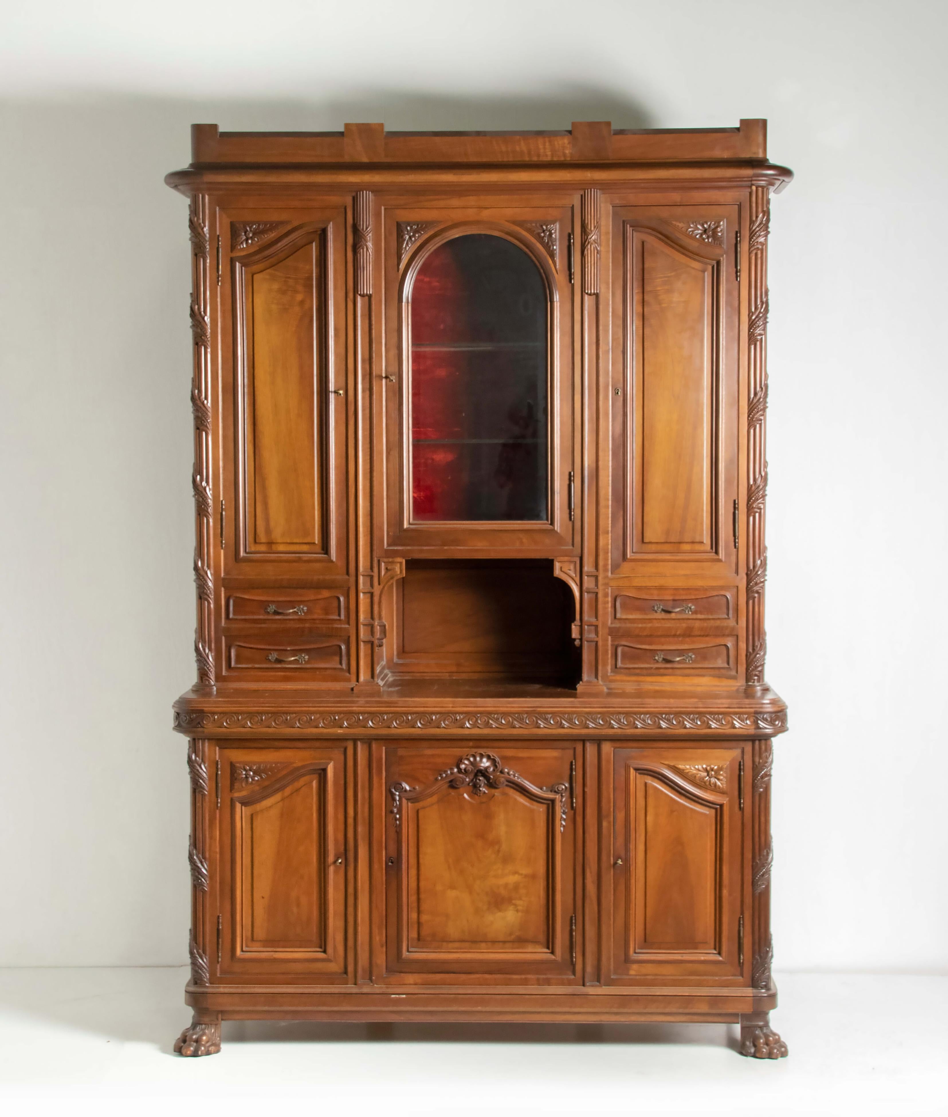 A late 19th century Louis XVI style solid walnut cabinet. Richly embellished with refined carving. At the center an arched glass door, the inside is lined with velvet fabric, originally this part was for storing silverware. The 
The lower part has
