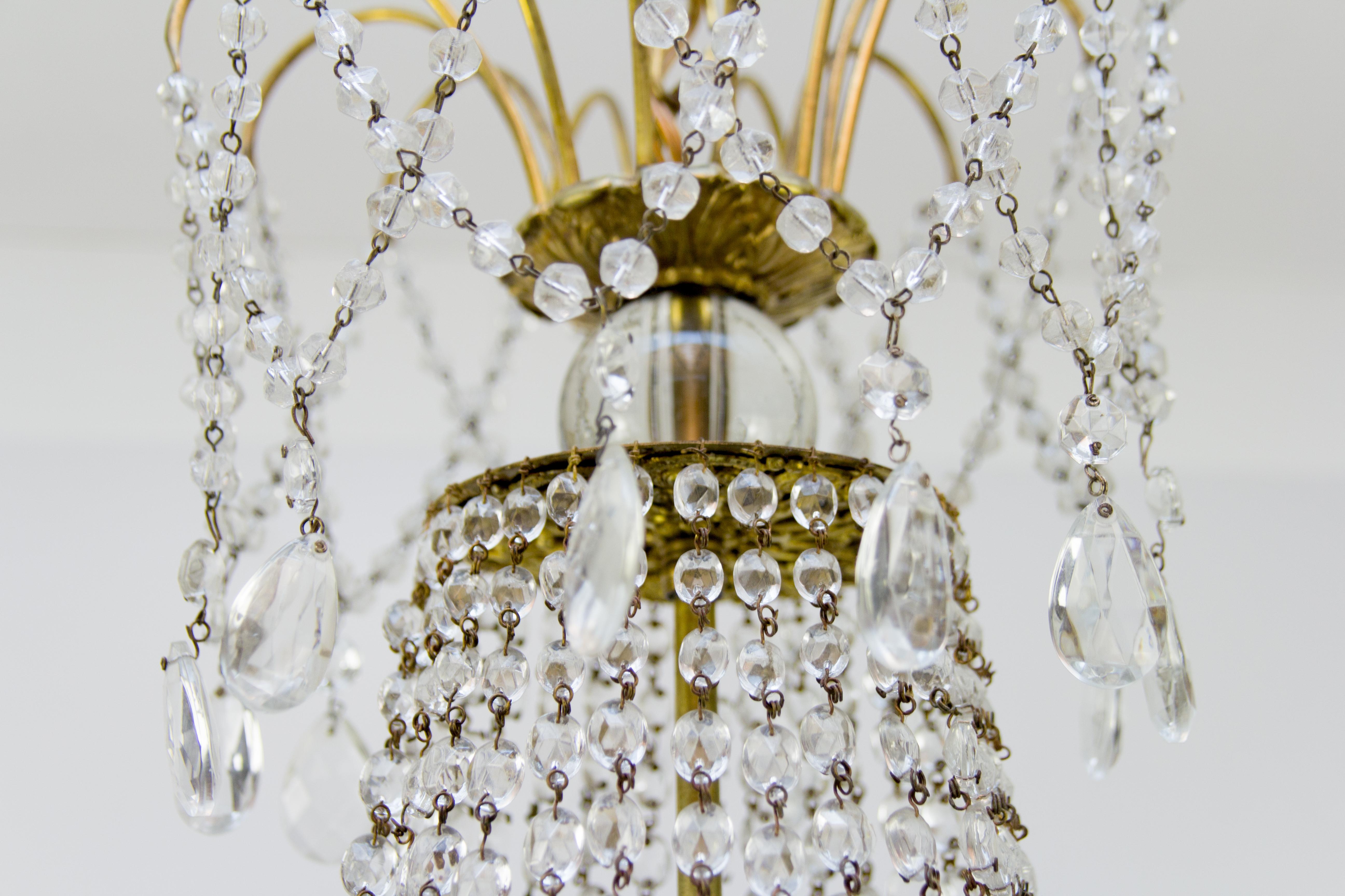 Beautiful, subtle late 19th century Louis XVI style brass and crystal basket chandelier with a fountain corona, having an elegantly draped canopy with cascading bead crystals and almond-shaped prisms. Six perimeter candle arms, each with one light.
